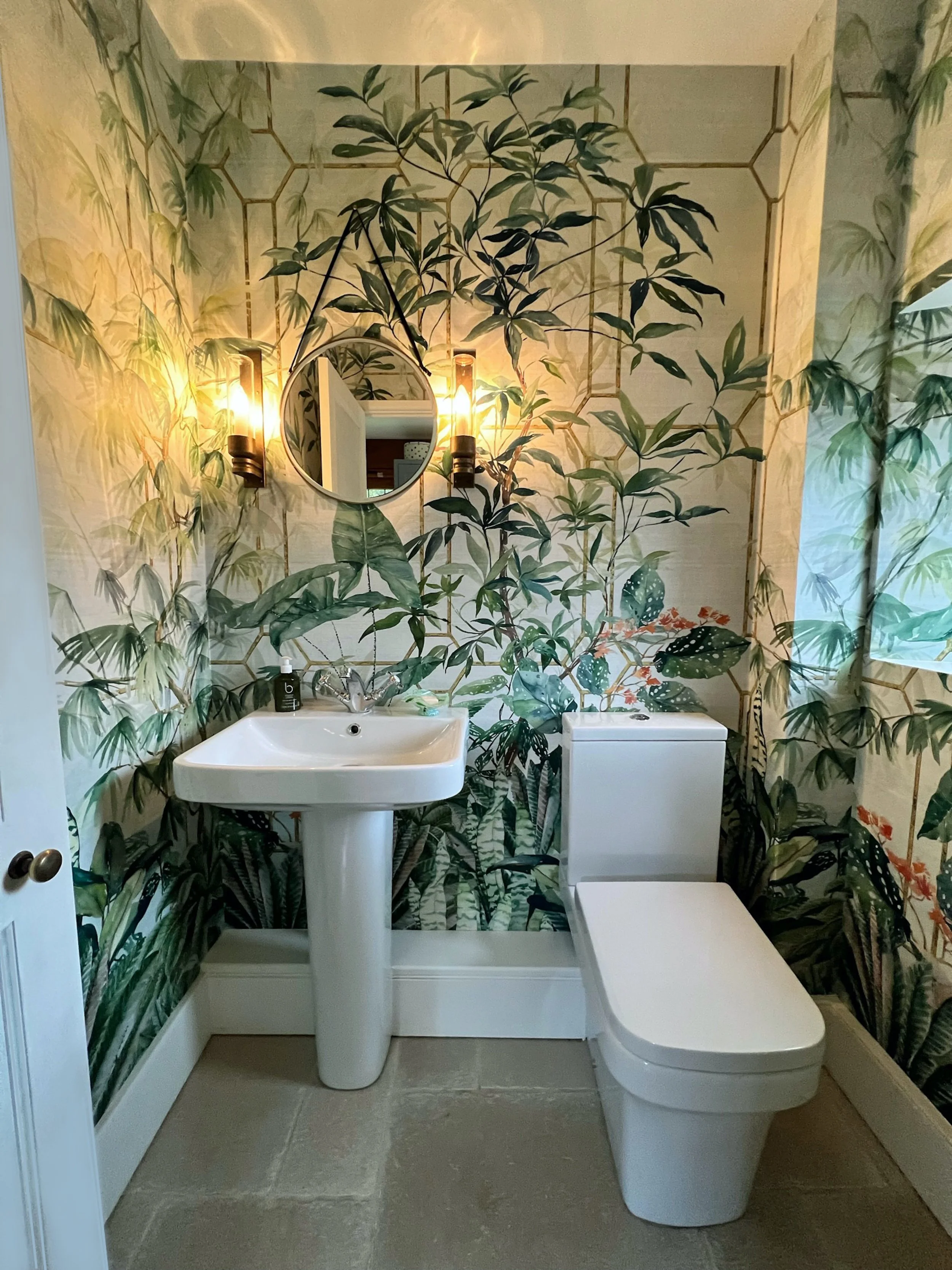 Ground floor cloakroom transformed with new sanitaryware, stone flooring and an immersive botanical wallpaper mural in rich green tones.