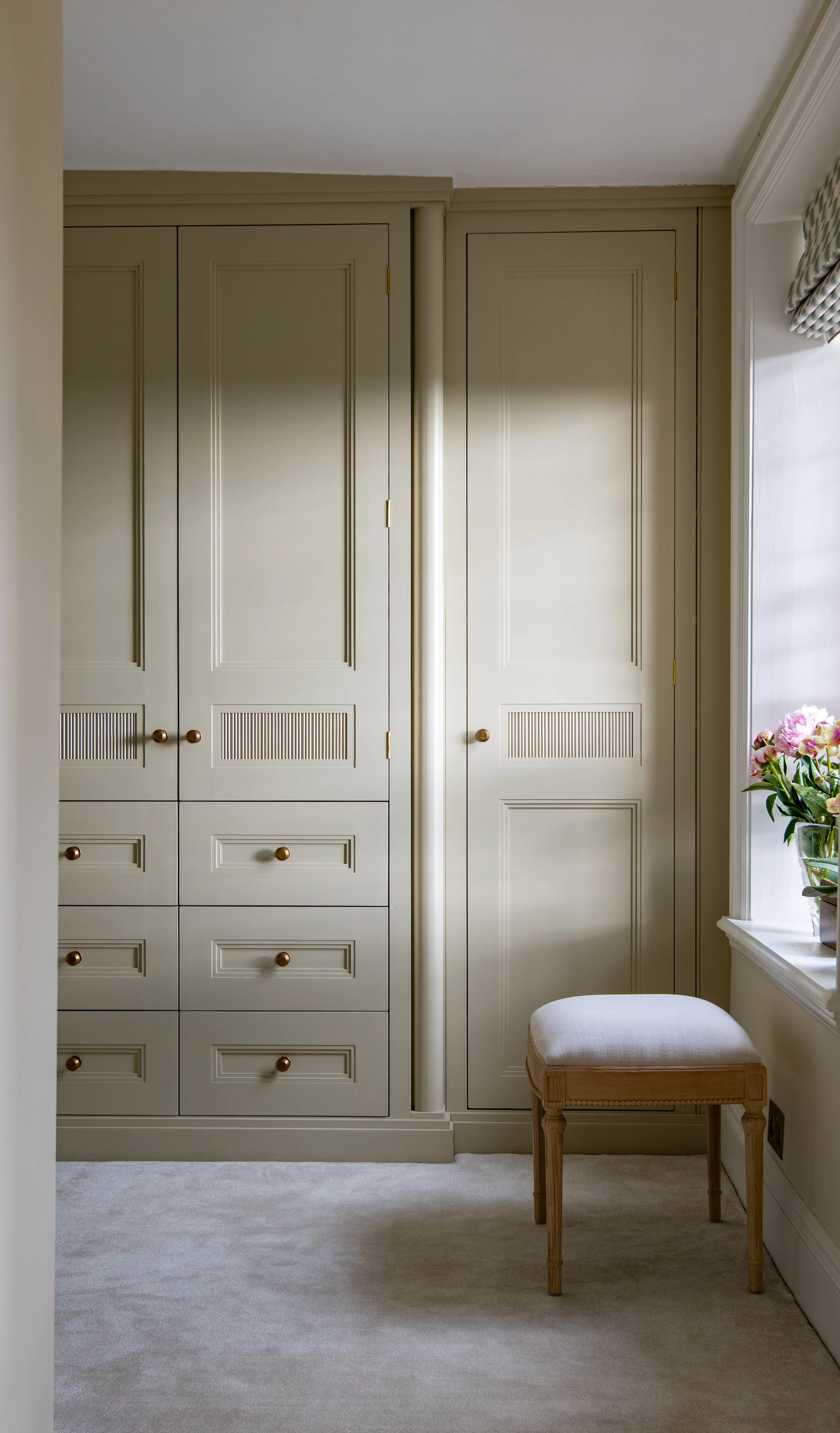 Master dressing room designed by MIDA Interiors for a large Cotswolds country estate, featuring bespoke wardrobes, integrated drawers, concealed storage, brass hardware and a reconfigured layout that increases the usable dressing-room footprint.