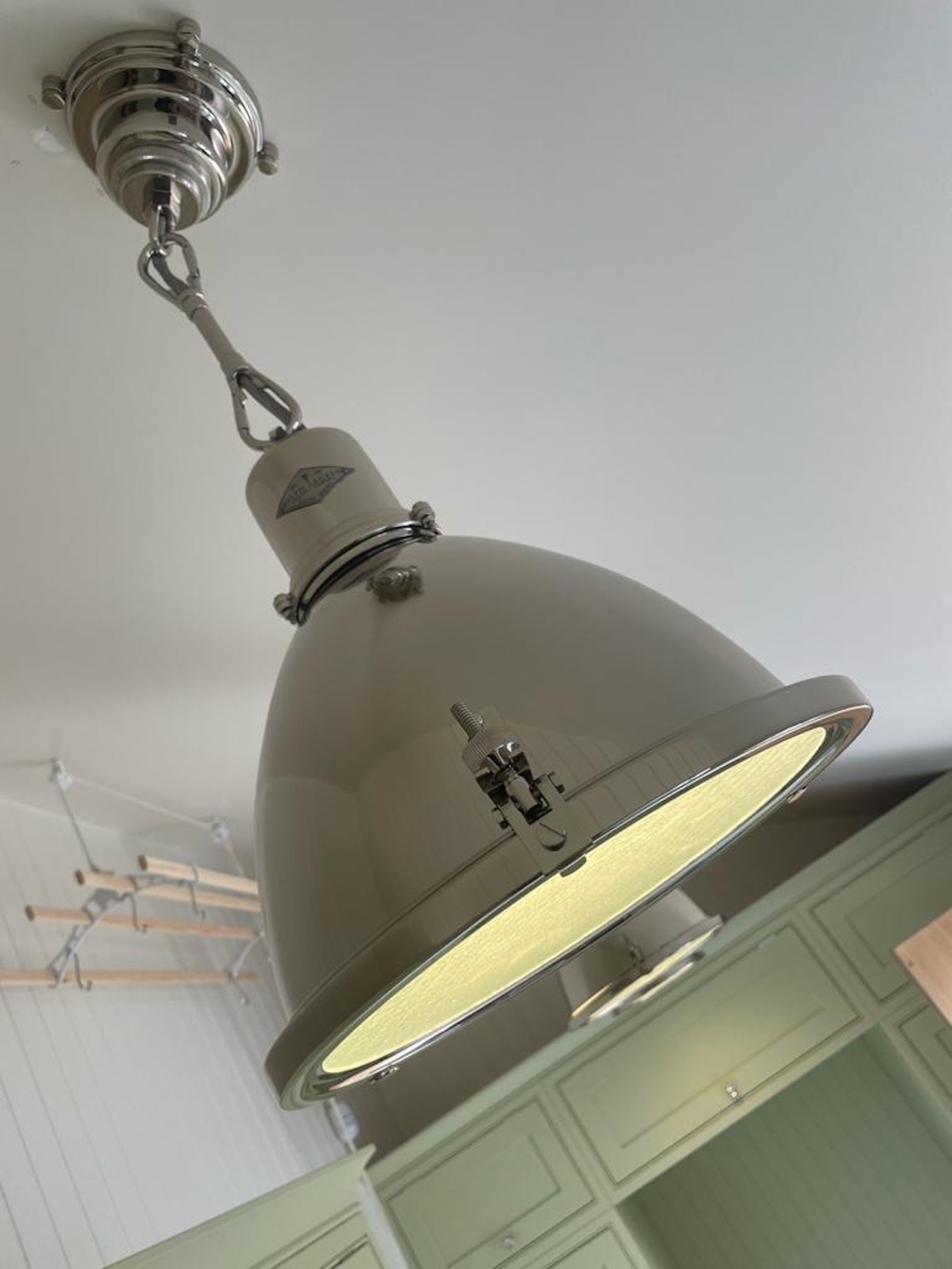 A close view of one of the industrial-style pendant lights specified for the Grade II listed farmhouse boot room and utility. The generous enamelled metal shade directs light onto the working areas below, while polished nickel suspension fittings int