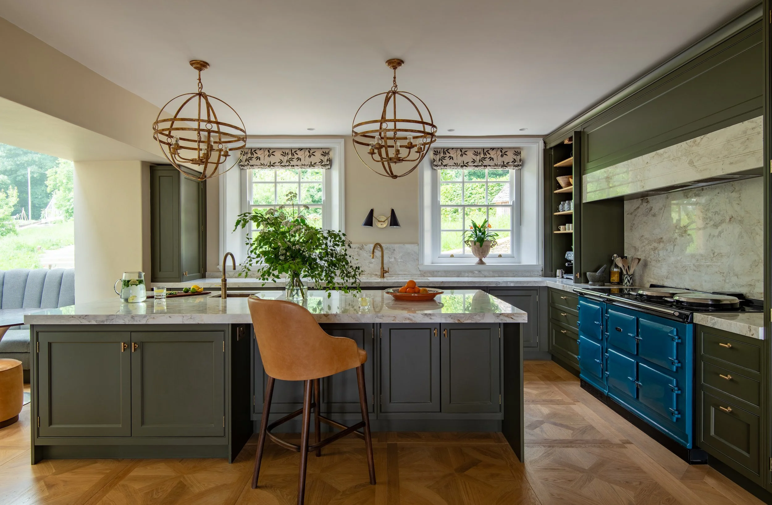 Bespoke kitchen reconfigured and designed by MIDA Interiors for a large Cotswolds country estate, featuring handcrafted cabinetry, a generous island planned around the client’s cooking style, a teal electric Aga and Calacatta Firenze stone sourced fr
