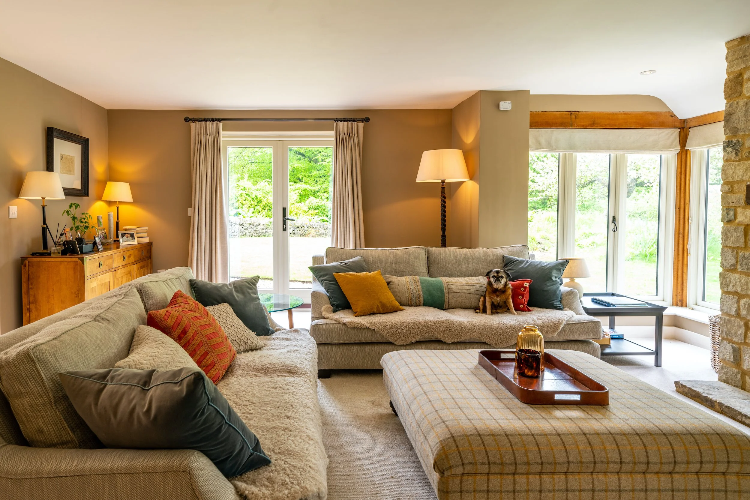 Family living room designed by MIDA Interiors for an Oxfordshire country home, featuring layered natural textiles, generous seating, warm neutral tones and garden views.