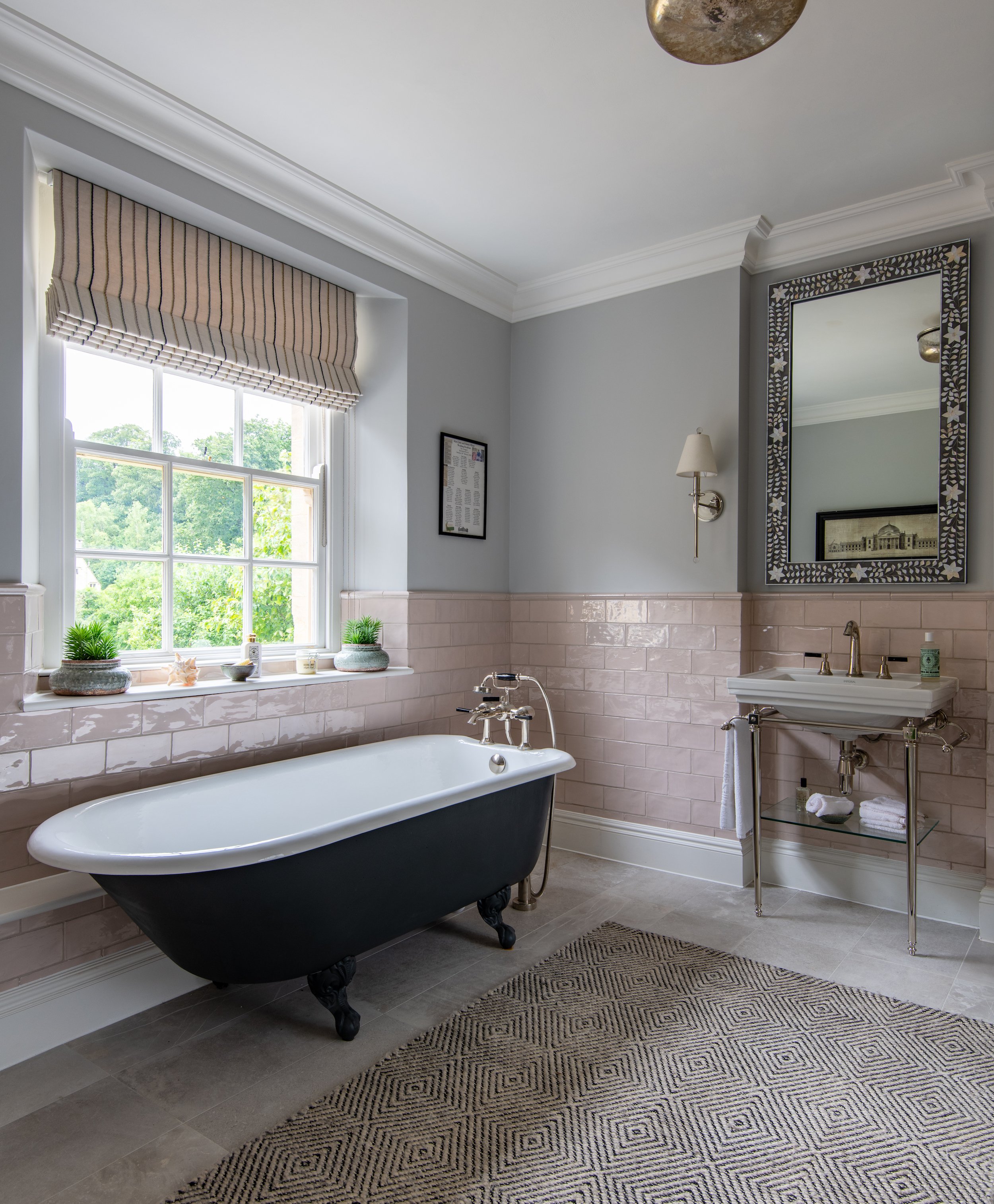 Guest bathroom designed by MIDA Interiors for a large Cotswolds country estate, featuring a freestanding roll-top bath, a generous three-sided shower, blush glazed wall tiles, traditional sanitaryware and a soft grey colour palette.