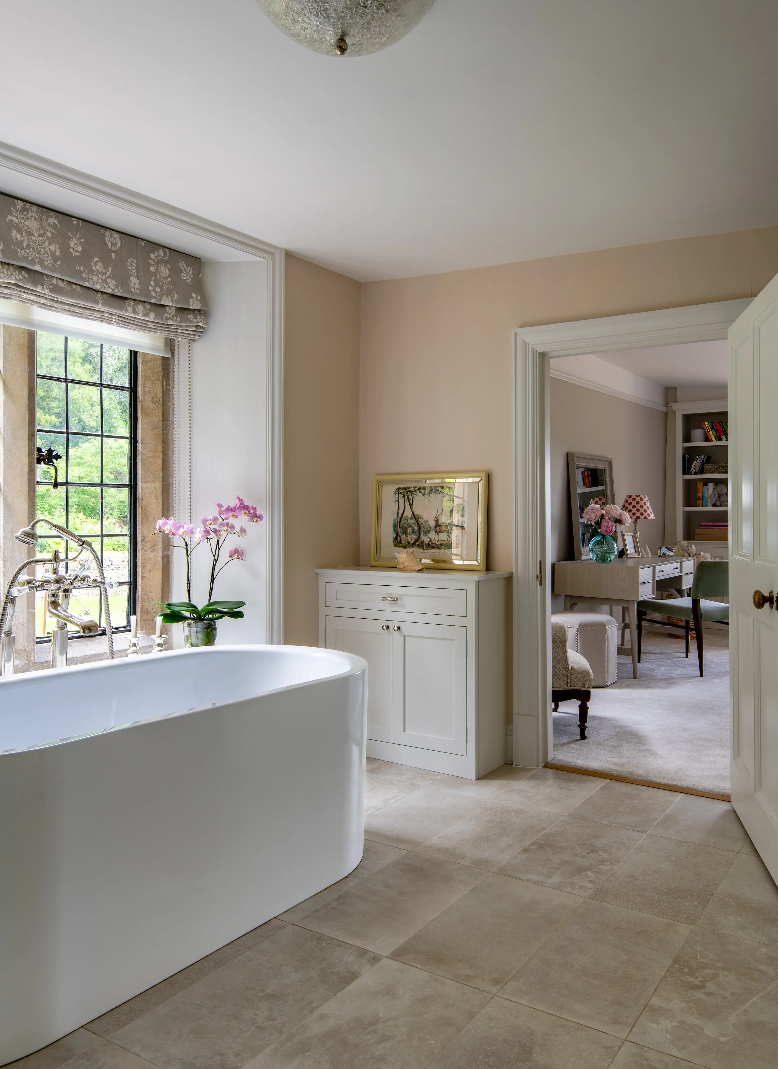 Children’s en-suite bathroom designed by MIDA Interiors for a large Cotswolds country estate, reconfigured to improve circulation between the bedroom, bathroom and dressing room, with a freestanding bath, bespoke storage and natural light.