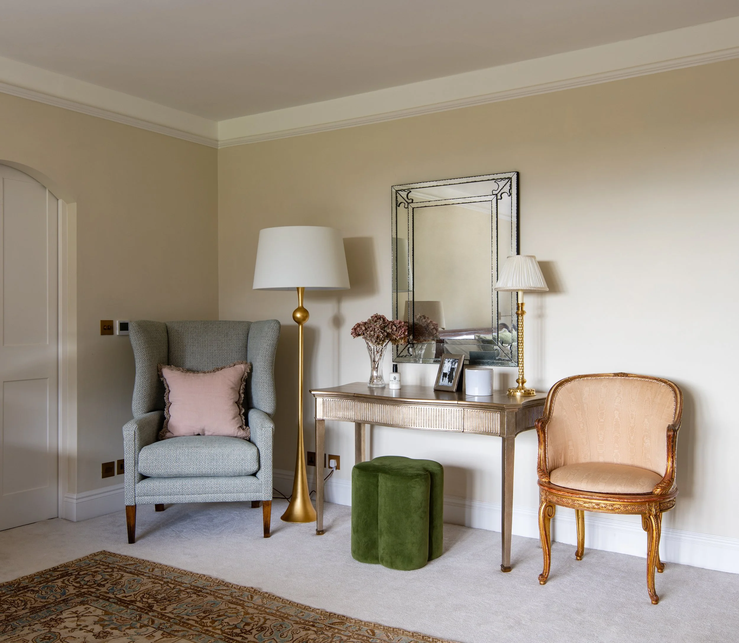 Master bedroom dressing area designed by MIDA Interiors for a large Cotswolds country estate, featuring a refined dressing table, framed crystal mirror, bespoke upholstered wing chair, antique reupholstered French chair and layered contemporary light