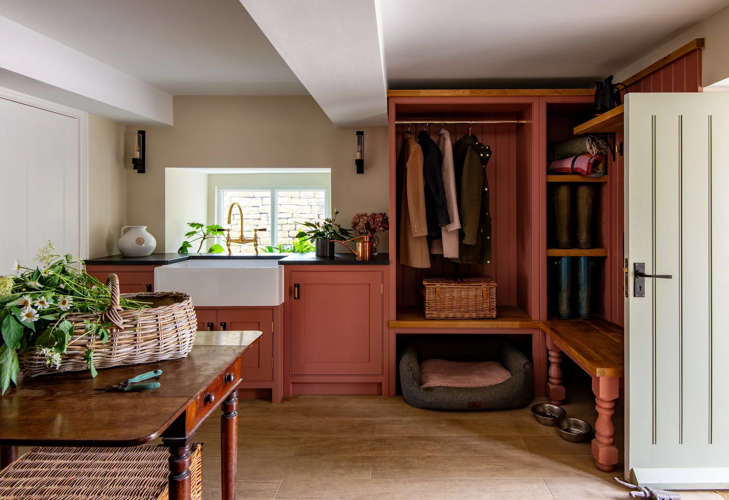 Elegant boot room designed by MIDA Interiors for a large Cotswolds country estate, featuring handcrafted painted joinery, generous coat and boot storage, an integrated bench and a durable faux-wood tiled floor.