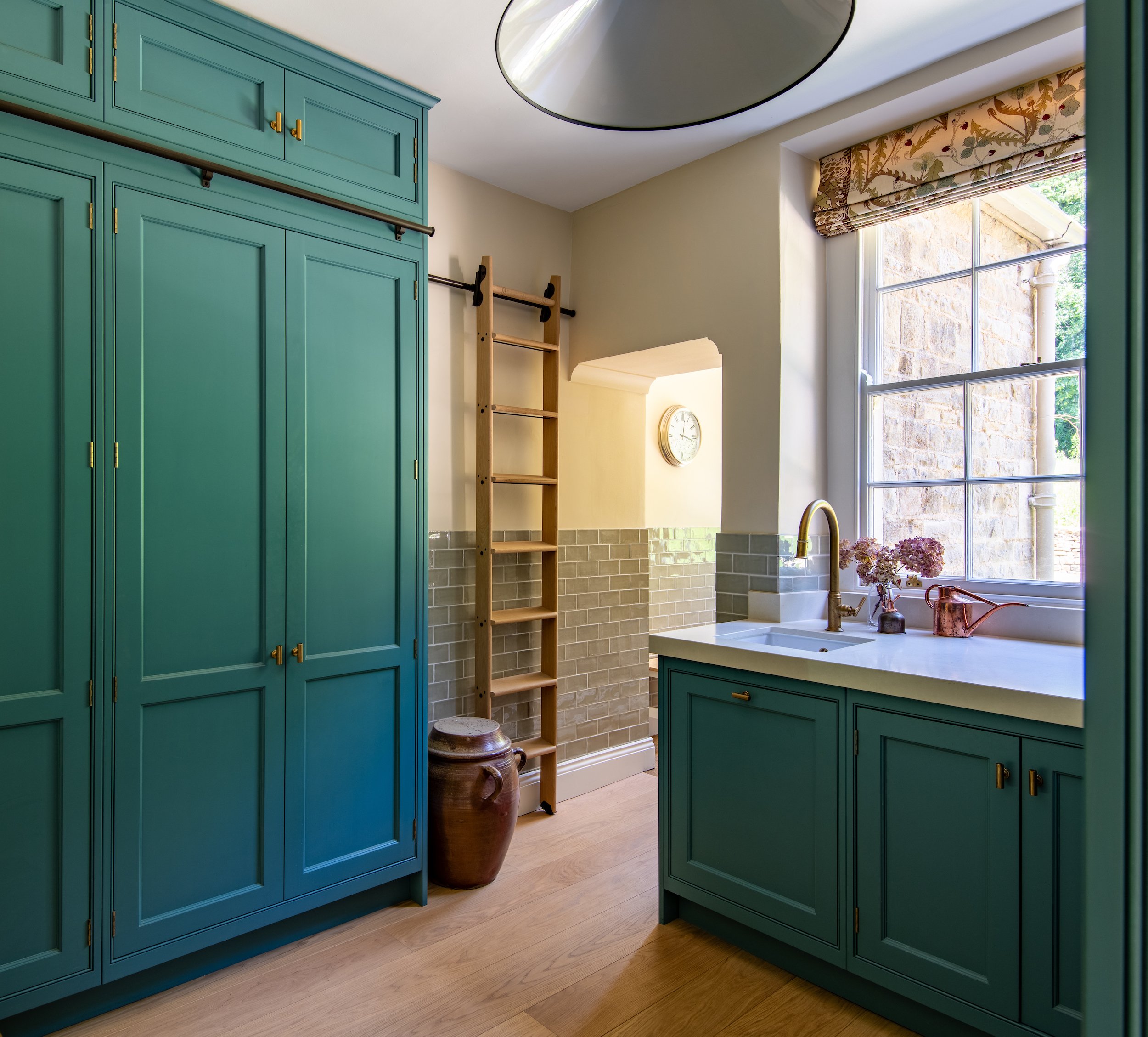 Pantry designed by MIDA Interiors for a large Cotswolds country estate, featuring full-height bespoke cabinetry, a removable oak library ladder, a reconfigured layout and a reinstated historic back door previously concealed behind a cold room.