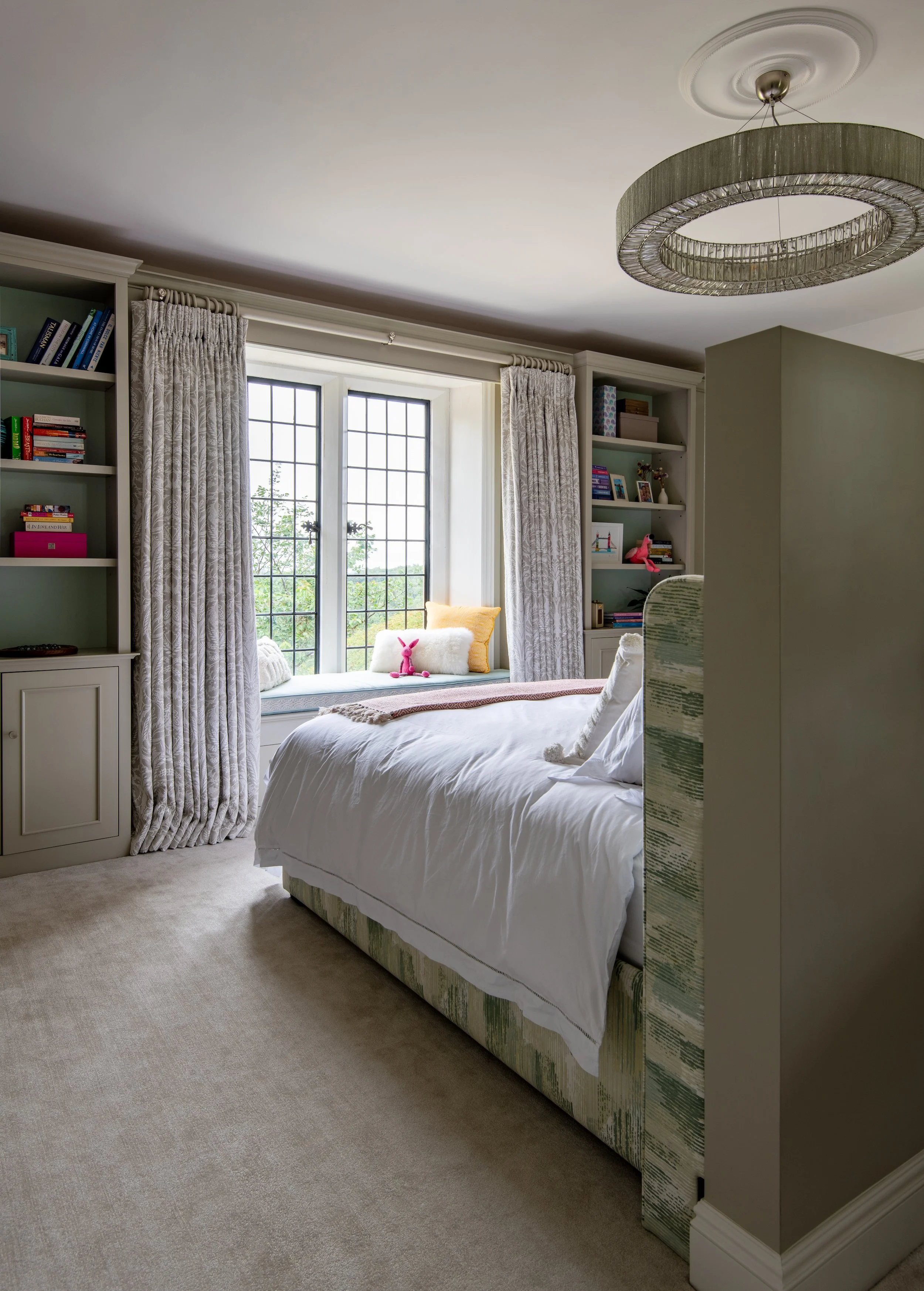Children’s bedroom designed by MIDA Interiors for a large Cotswolds country estate, featuring full-height bespoke cabinetry, mirrored storage, integrated shelving and an upholstered bed within a reconfigured layout.
