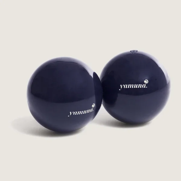 Two dark blue Yamuna exercise balls on a light background.