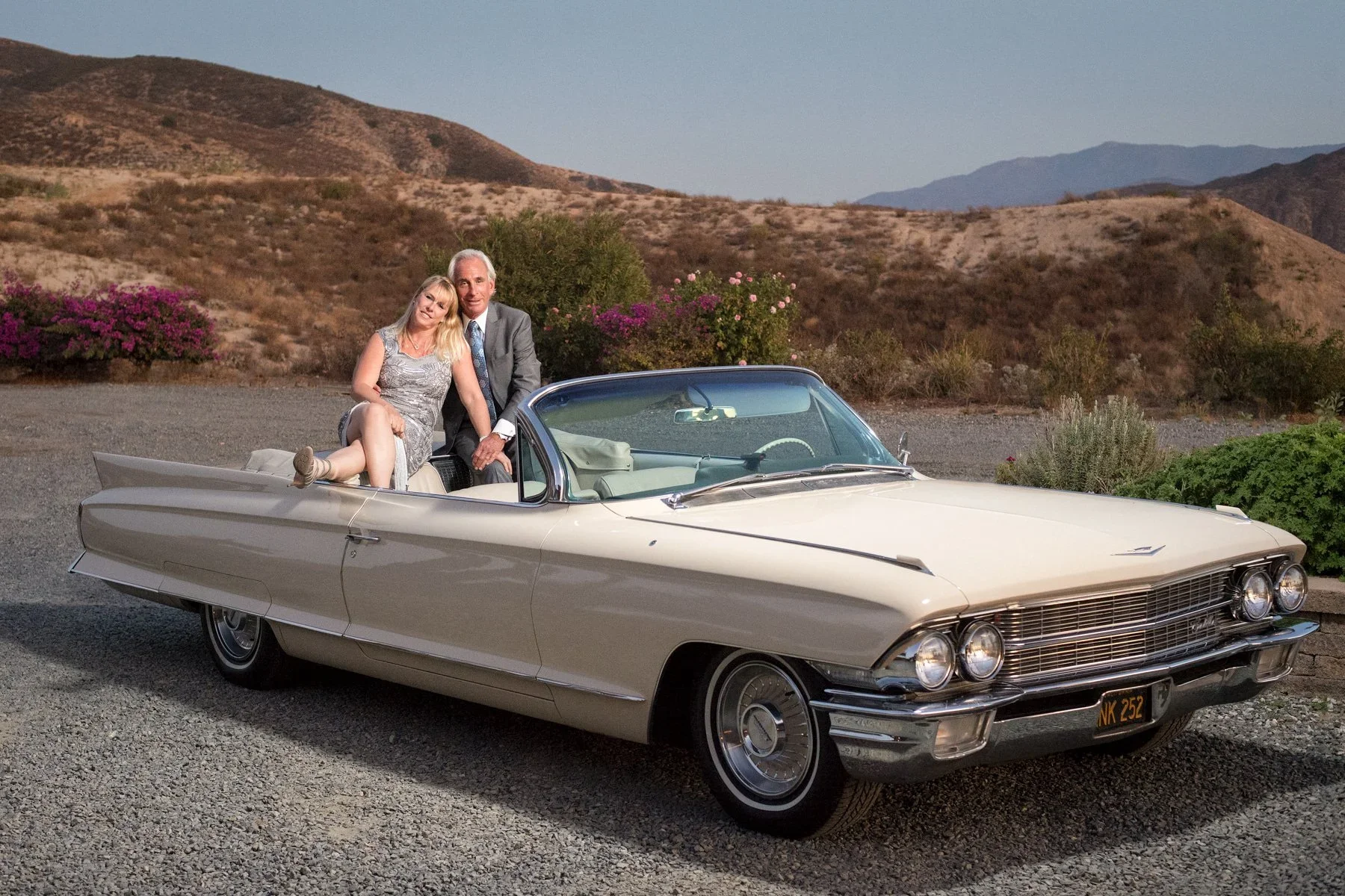 Owners Christina and Ken Falik sit in a vintage car with the panoramic views from the Gershon Bachus hilltop in the background