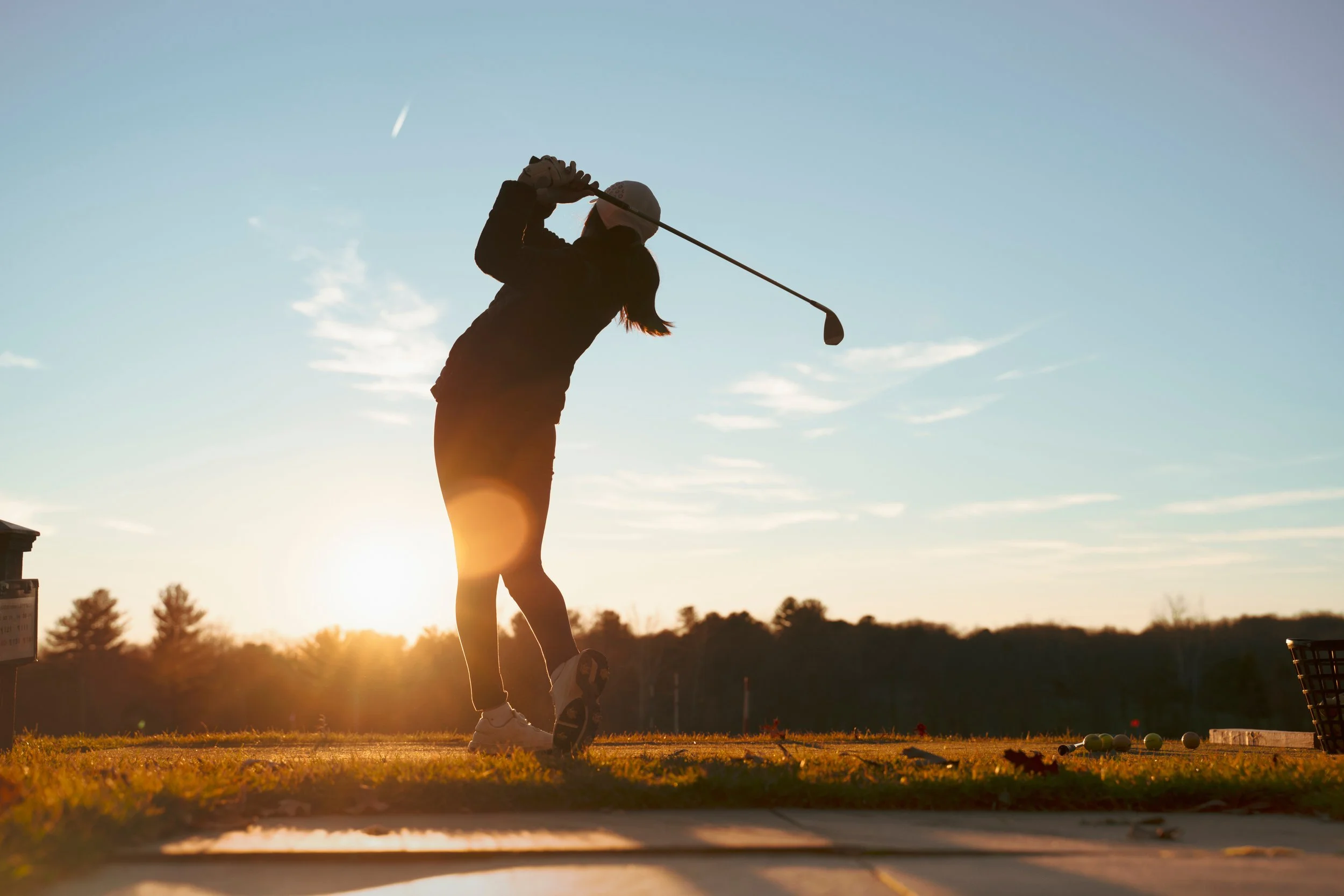 a silhouette of a women completing a golf swing