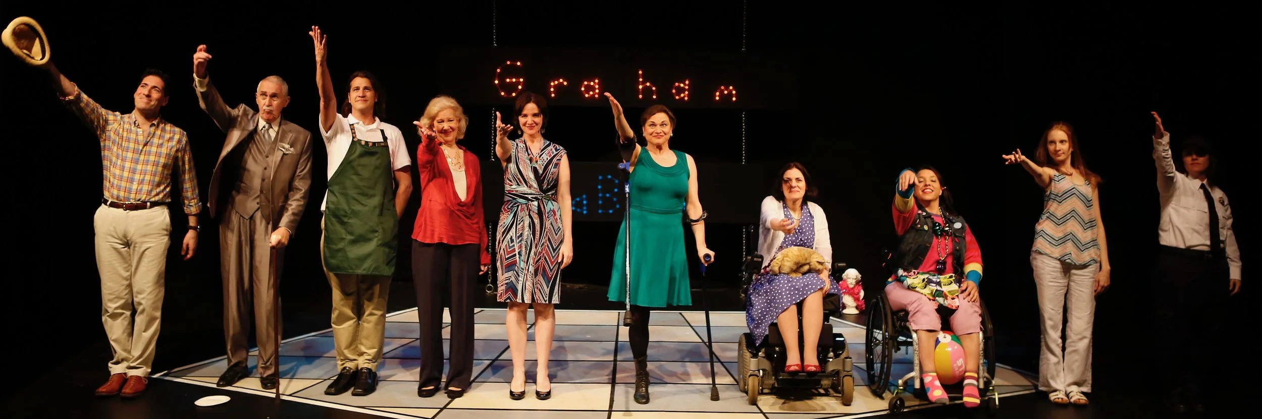 A picture of 10 TBTB actors, taking a bow on a stage. One actor has a cane, another one is on crutches and the other two are in wheelchairs.