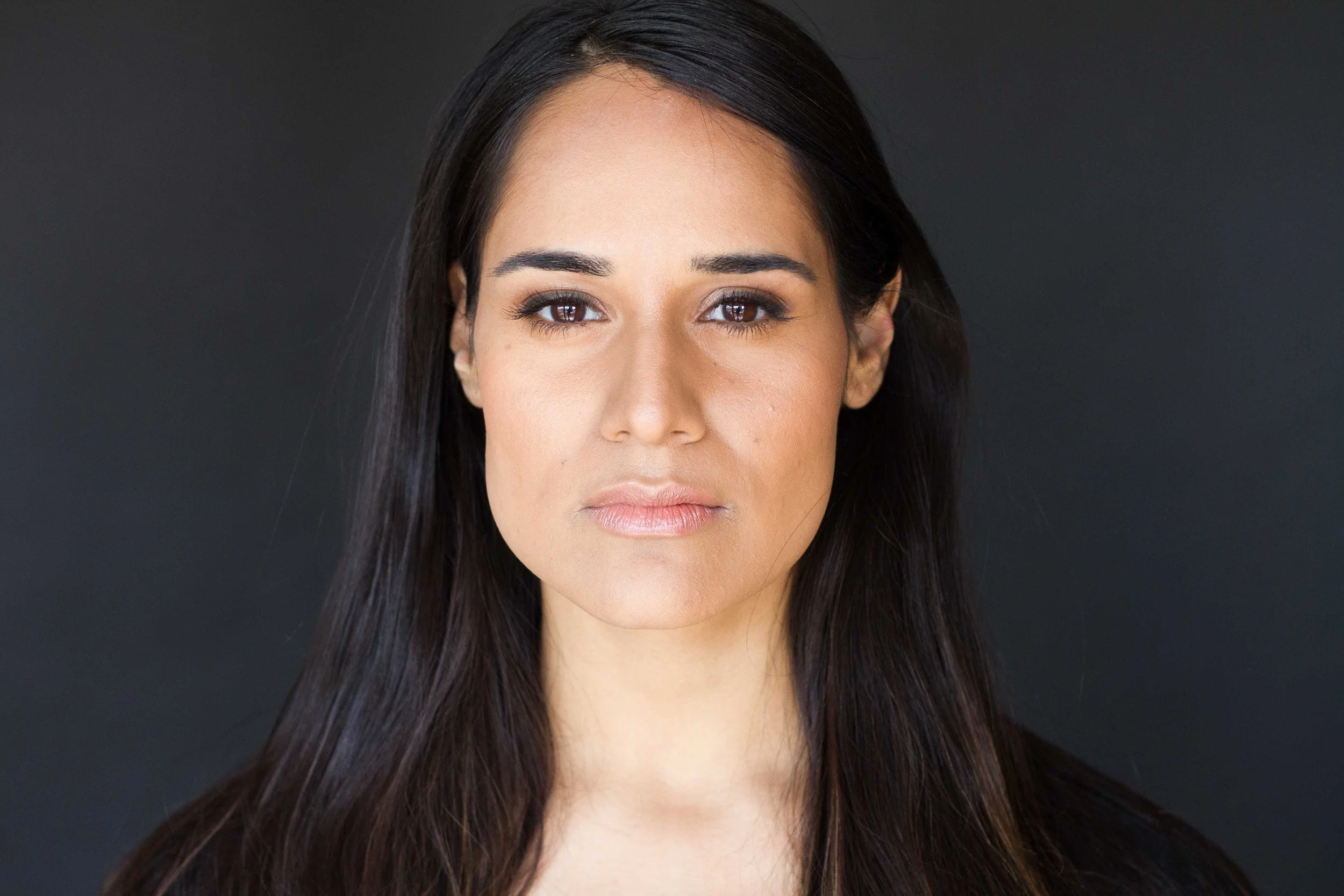 Fareeda Pasha, Board Member. A woman in her 30's, brown skin, brown eyes and long black hair. She is in front of a black drop.