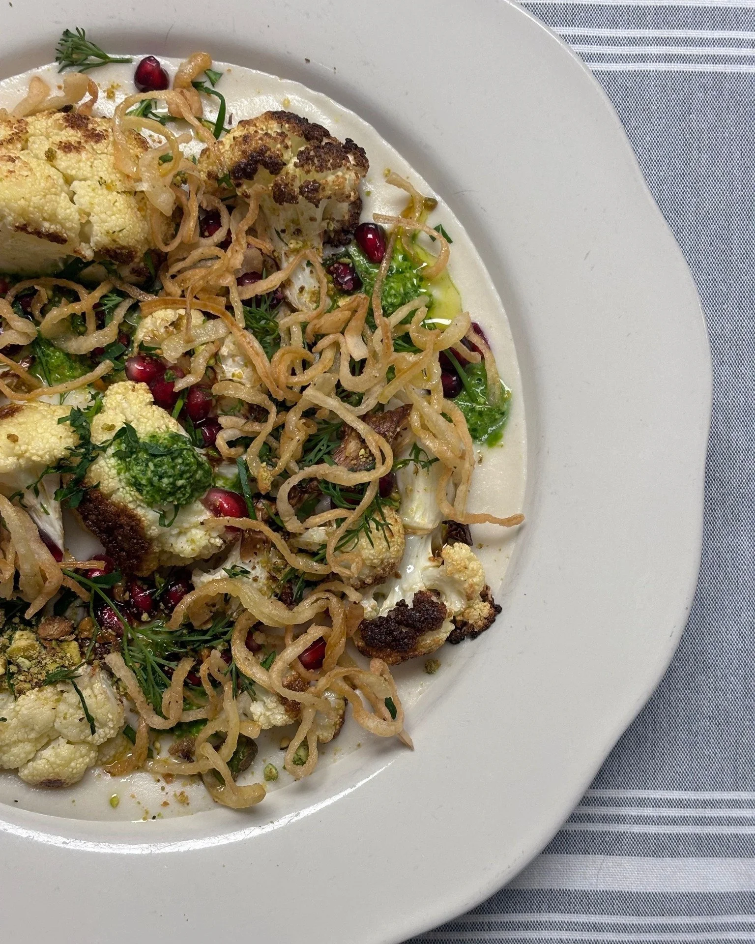 here we go...
roasted cauliflower in a pool of cauliflower-cashew purée topped with fresh herbs, cilantro chutney, pomegranate seeds, pistachios & crispy fried onions 
(plant-based 🌱)