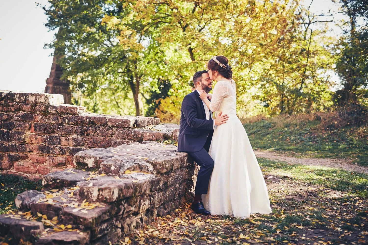 Braut küsst den Bräutigam auf die Stirn auf den Steinstufen der Klosterruine Limburg in Bad Dürkheim, Hochzeitsfoto im Herbst