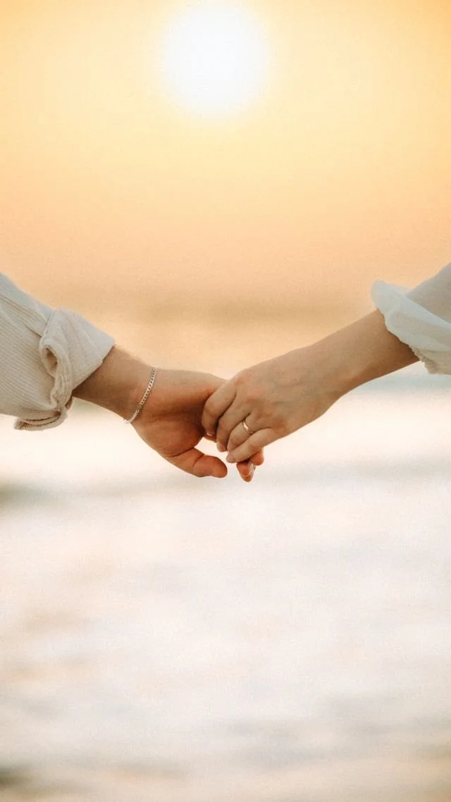 Close up of couple holding hands, only showing hands with sunny background