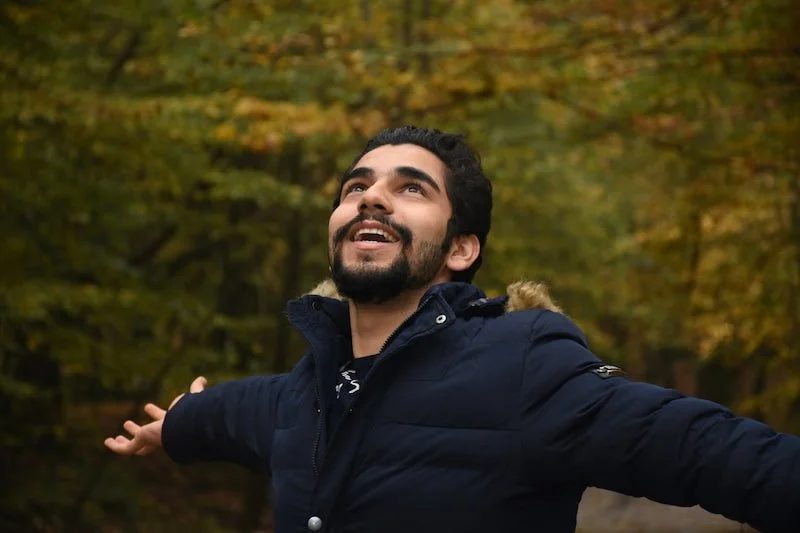 a smiling guy outside with a coat on