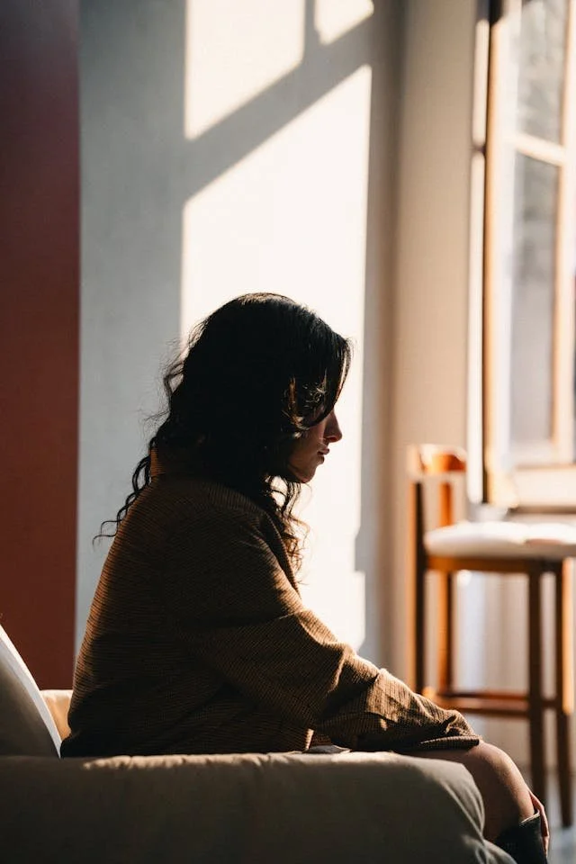 a woman sitting in a chair looking down with long hair