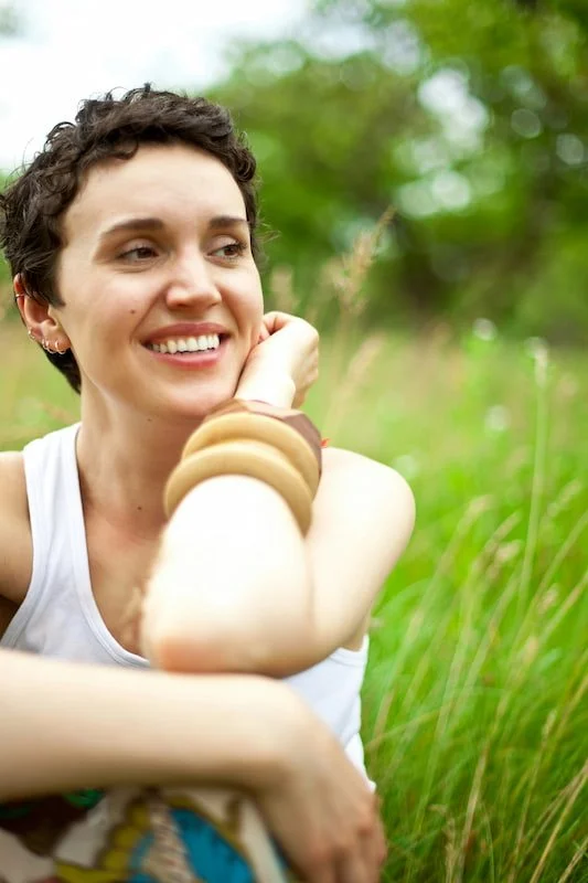 a woman smiling outside in green grass
