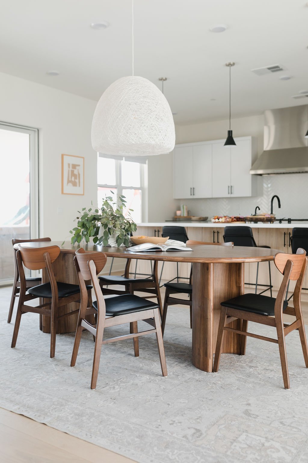 Open floor plan dining room, grounded with a light fixture and rug.