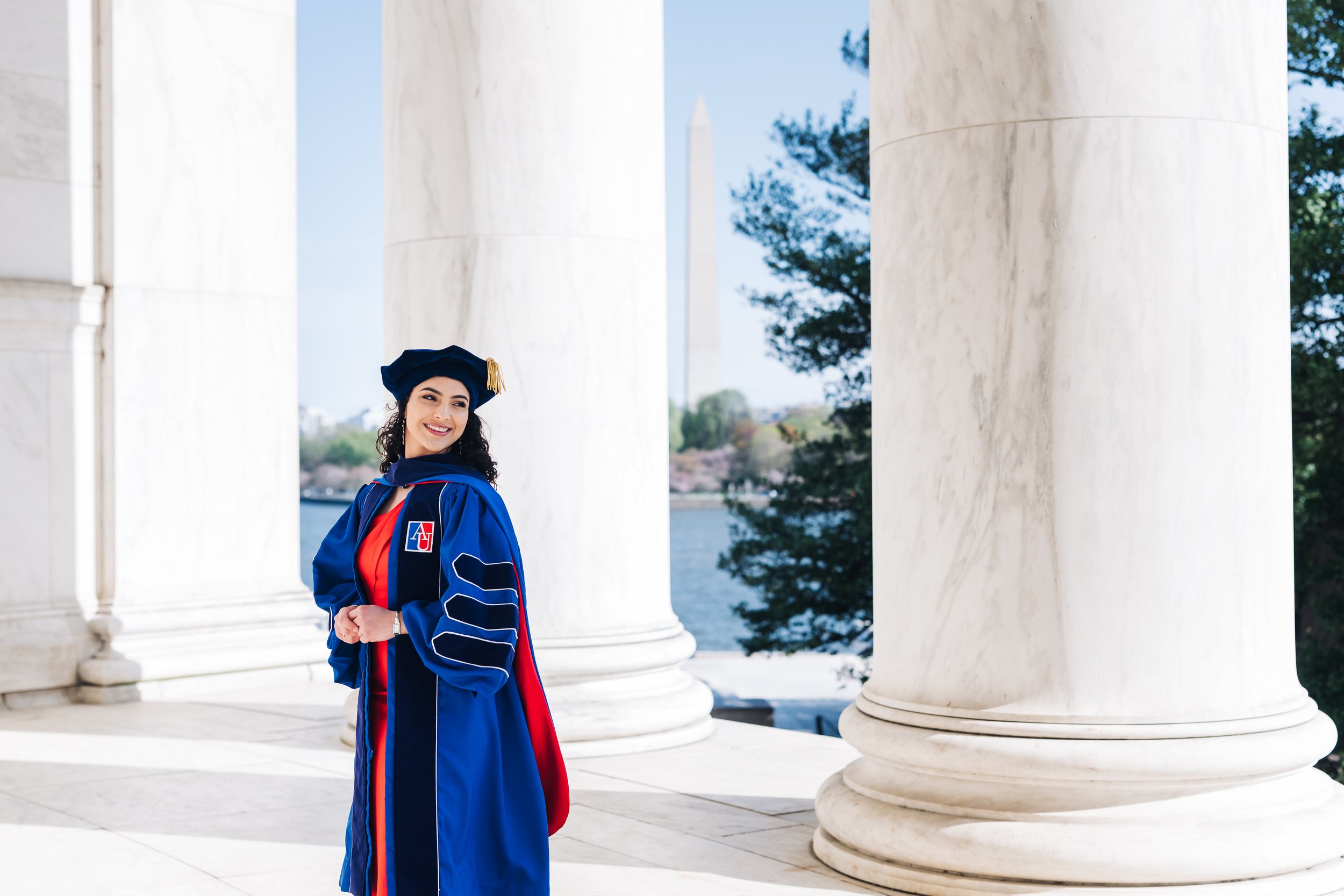 Graduate in red dress and cap and gown at Jefferson memorial