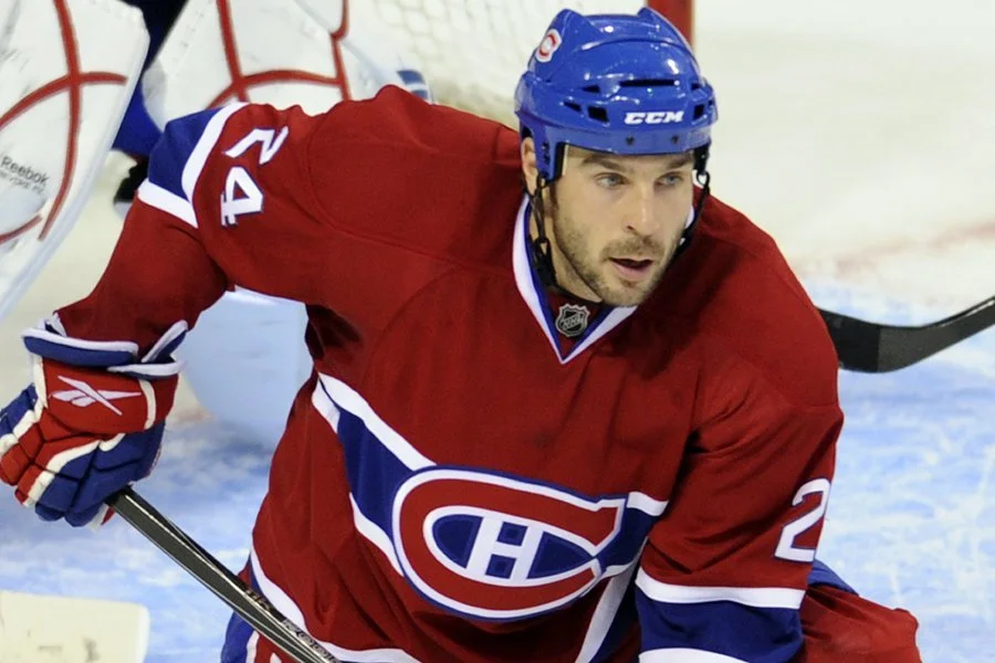 Hockey player in a red Canadiens jersey and blue helmet on ice.