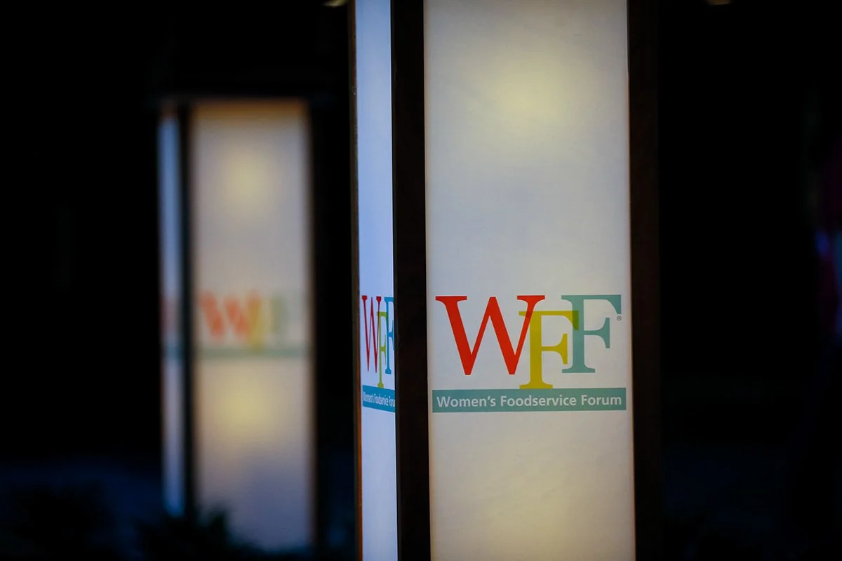 A close-up of a sign that reads "Women's Foodservice Forum" with the acronym "WFF" in colorful letters.