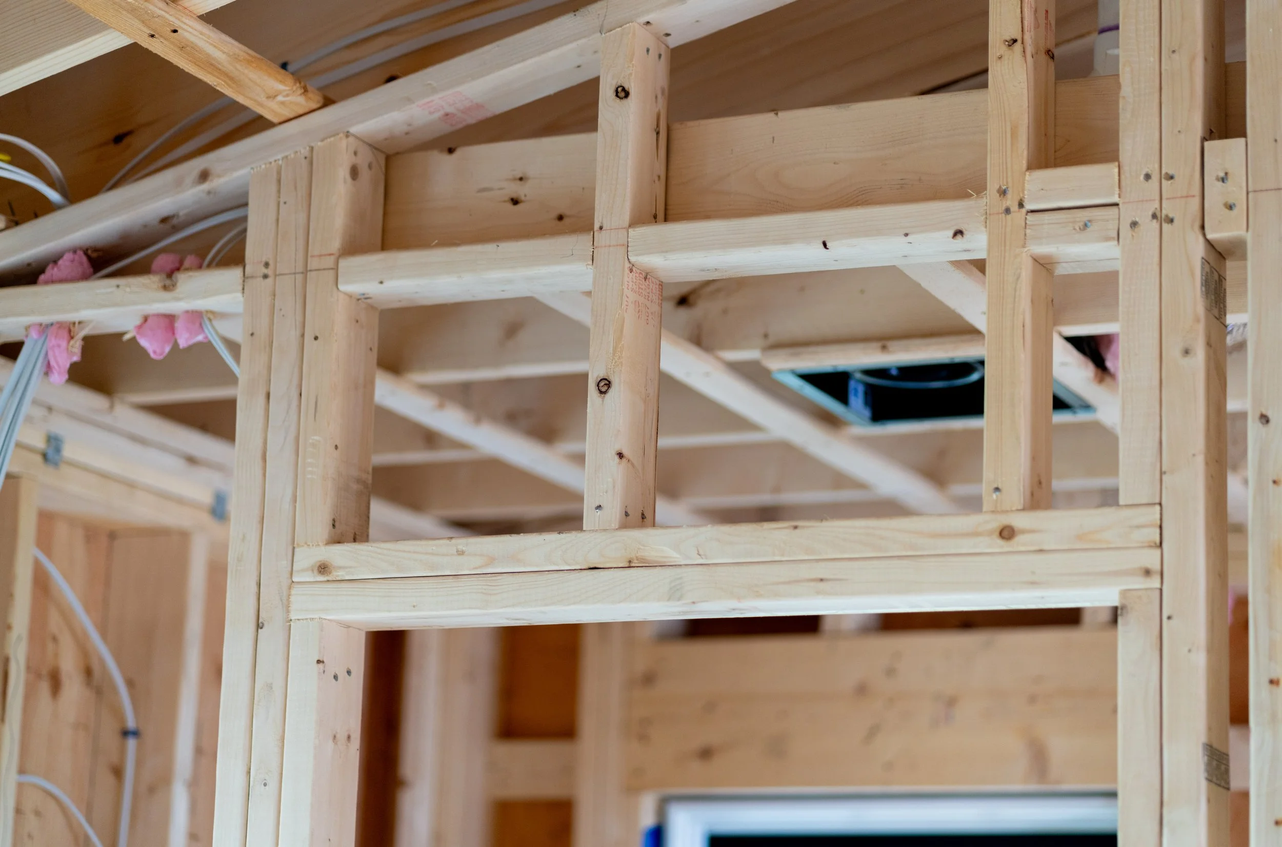 Wooden framing of a building under construction with electrical wiring visible.