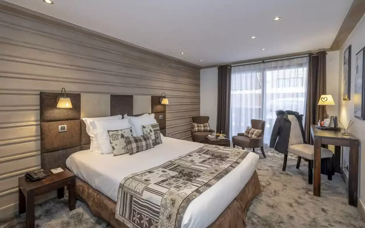 Hotel room at La Chaudanne Méribel, with textured walls and a large bed decorated with mountain motifs. A modern, comfortable space for Aylo Montagne seminar participants to relax in.