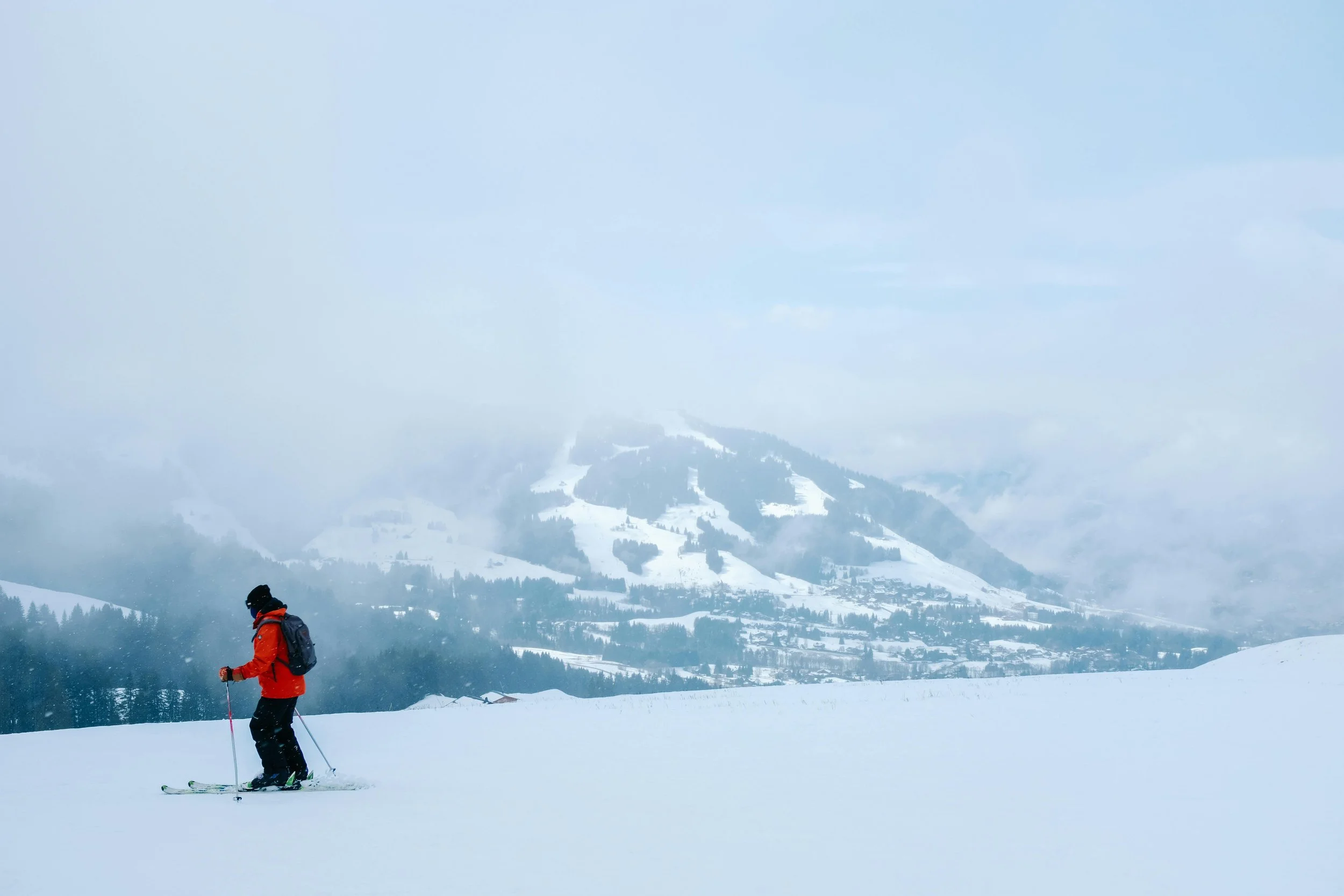 Un skieur de randonnée avec un sac à dos sur une piste enneigée de Saint Gervais, sous un ciel brumeux. La scène représente l'aventure de montagne pour un séminaire d'entreprise Aylo Montagne.