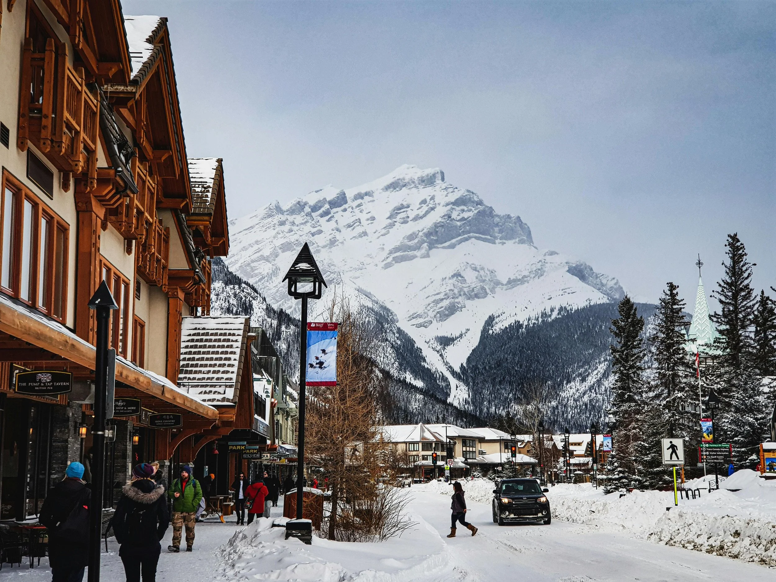 Centre du village de Gstaad en hiver, chalets traditionnels, passants dans la neige et montagnes suisses en arrière-plan – Aylo Montagne.