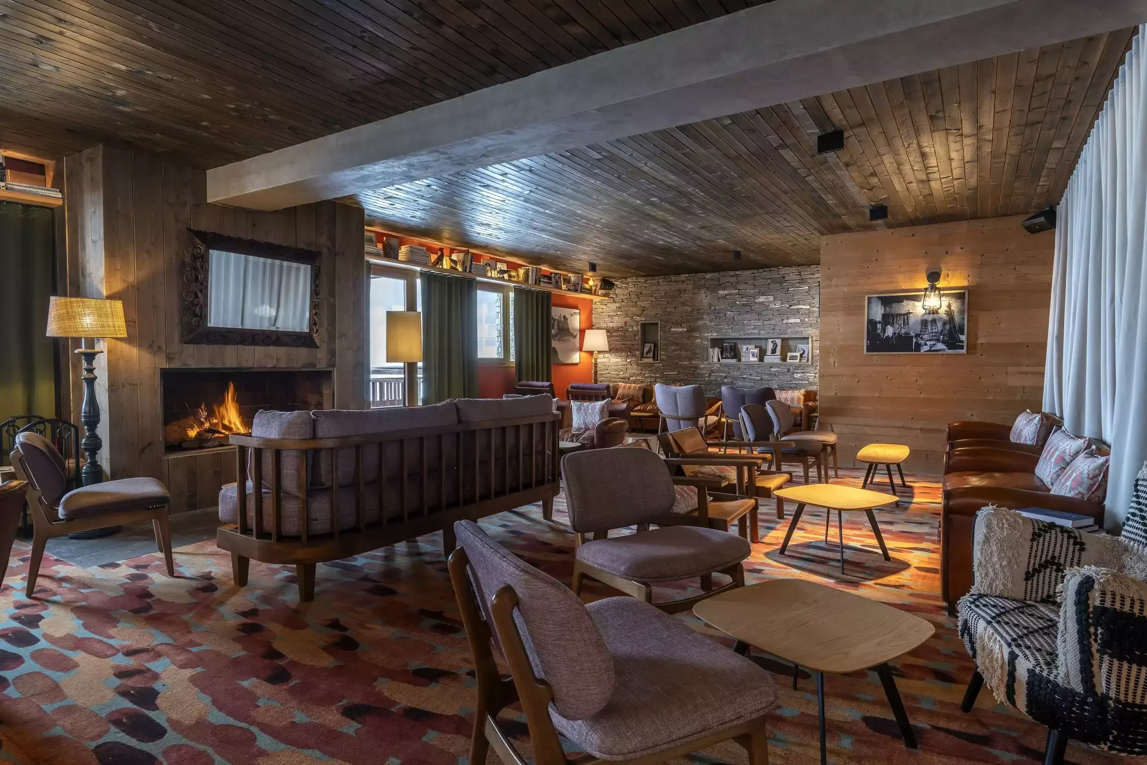 Hotel lounge at Hotel Kaya with a fireplace, comfortable sofas and wooden decor. It's a perfect space for relaxing and socializing, with a welcoming atmosphere.