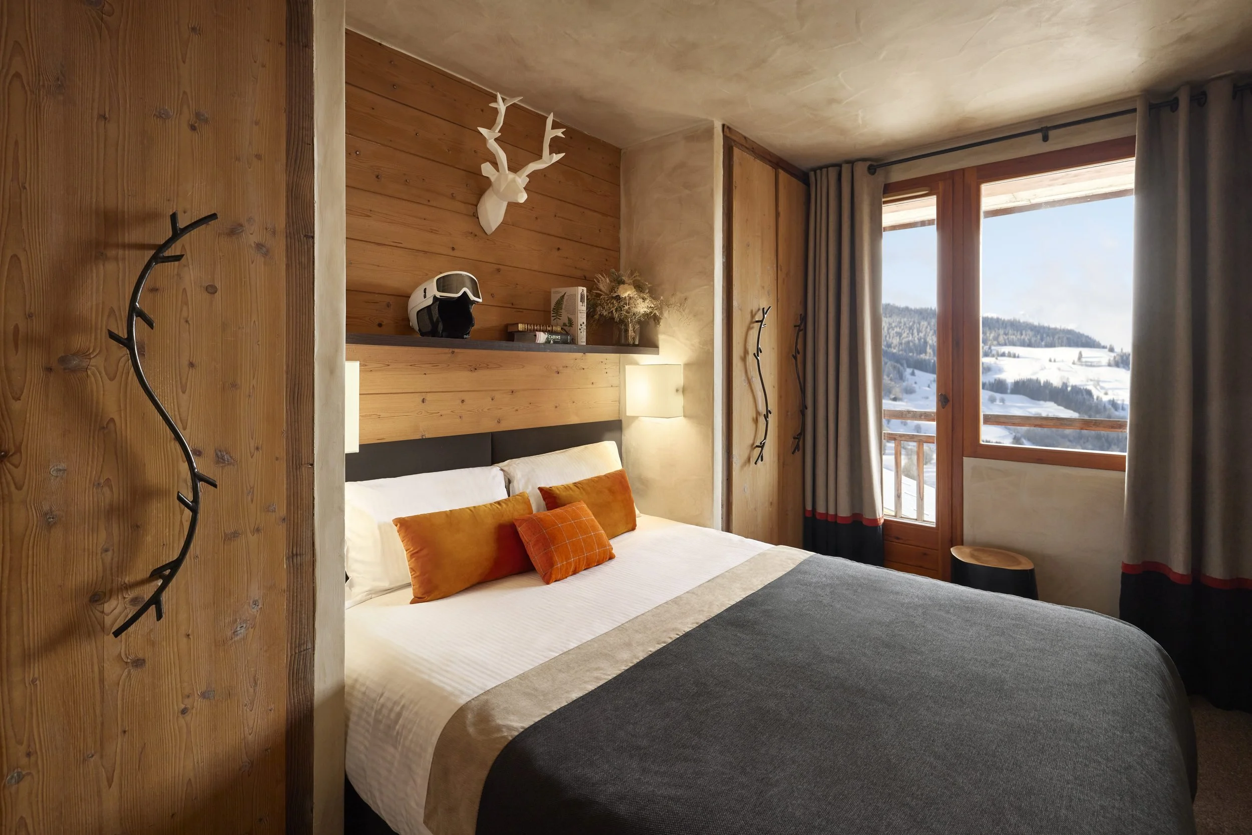 Chalet-style room at L'Arboisie Hôtel in Megève, with light wood walls, a comfortable bed and a window overlooking the winter landscape. A haven of peace for participants in an Aylo Montagne seminar.