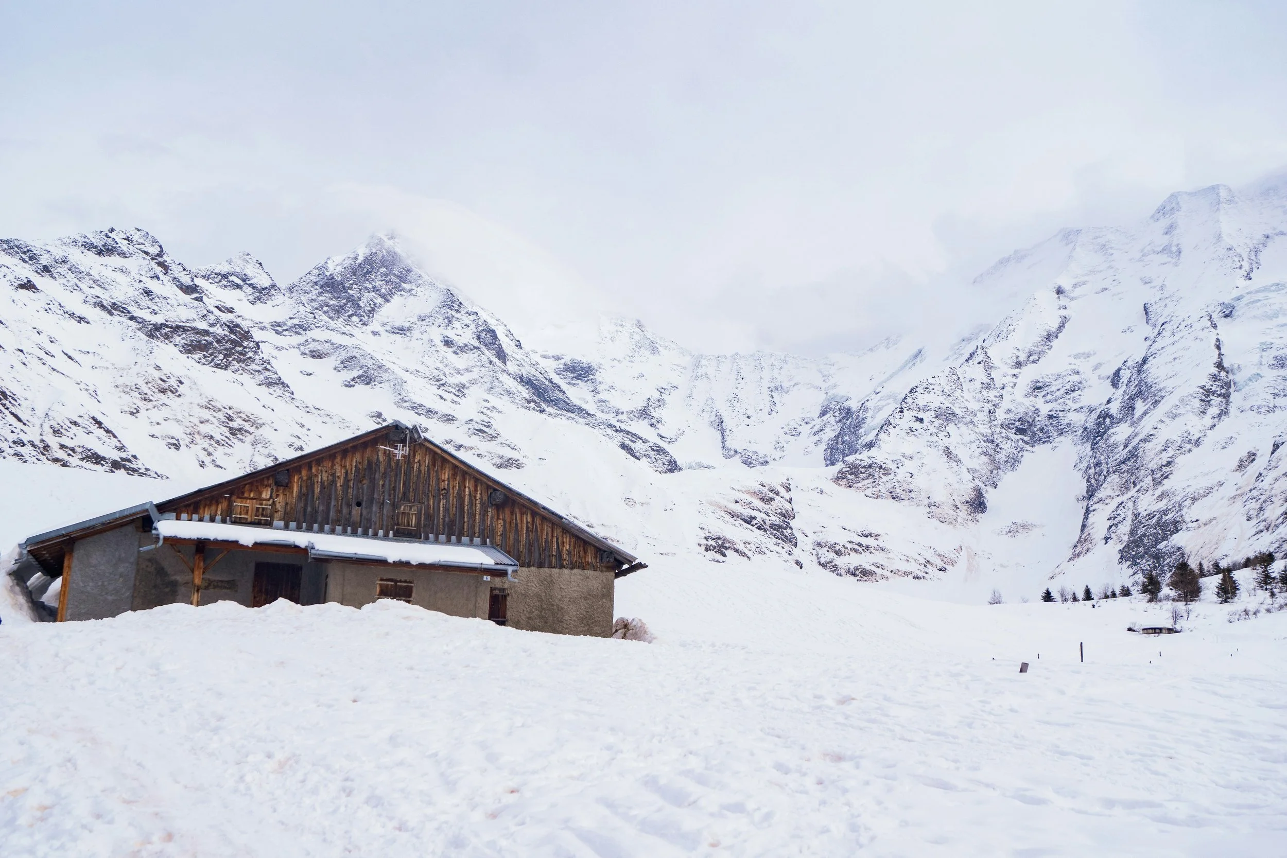 Vieux chalet de montagne rustique et isolé à Saint Gervais, avec un toit en bois et des murs en pierre, entouré de neige et de majestueux pics enneigés. Un cadre authentique pour un séminaire d'entreprise Aylo Montagne.