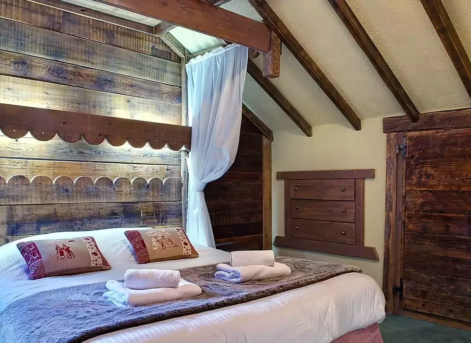 Rustic hotel room design at Le Meuire Chalet Hotel and Spa. Wooden walls and headboard give it a traditional, welcoming feel.