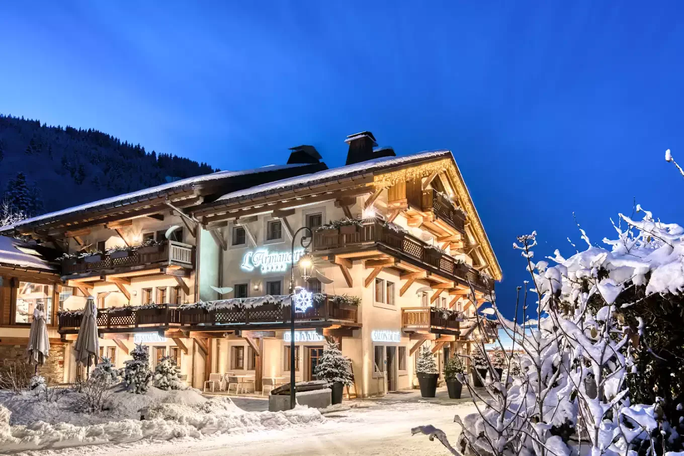 Façade illuminée de l'Hôtel Armancette à Saint Gervais la nuit. Ce luxueux chalet de bois est couvert de neige et représente le cadre idéal pour un séminaire
