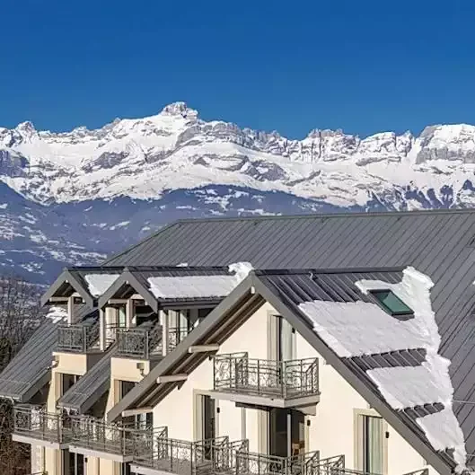 Façade extérieure de l'Hôtel Saint Gervais à la station de Saint Gervais ski. Le design alpin moderne avec toits pentus enneigés et balcons est parfait pour un séminaire d'entreprise Aylo Montagne.