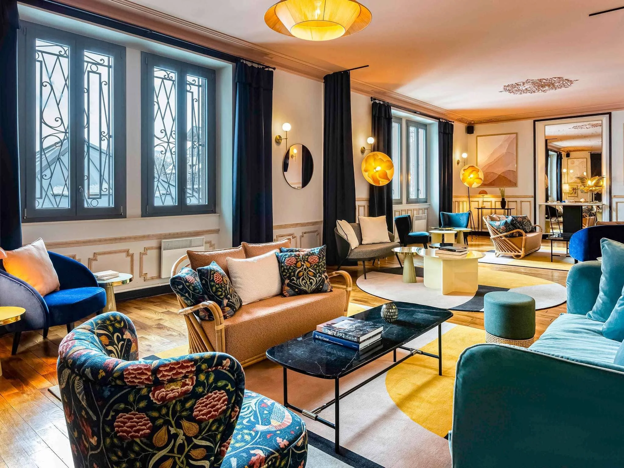 Lobby de l'Hôtel Saint Gervais avec un design contemporain et coloré, incluant des canapés en velours et des lumières modernes. Un espace élégant pour la cohésion d'équipe lors d'un séminaire d'entreprise Aylo Montagne.