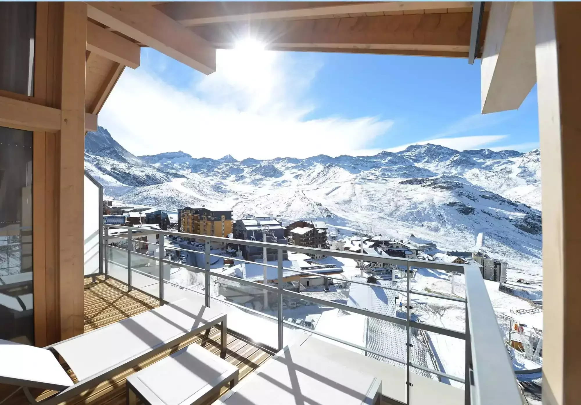 View from a balcony at Club Med Val Thorens Sensations over a breathtaking landscape of snow-capped mountains and chalets under a brilliant blue sky.