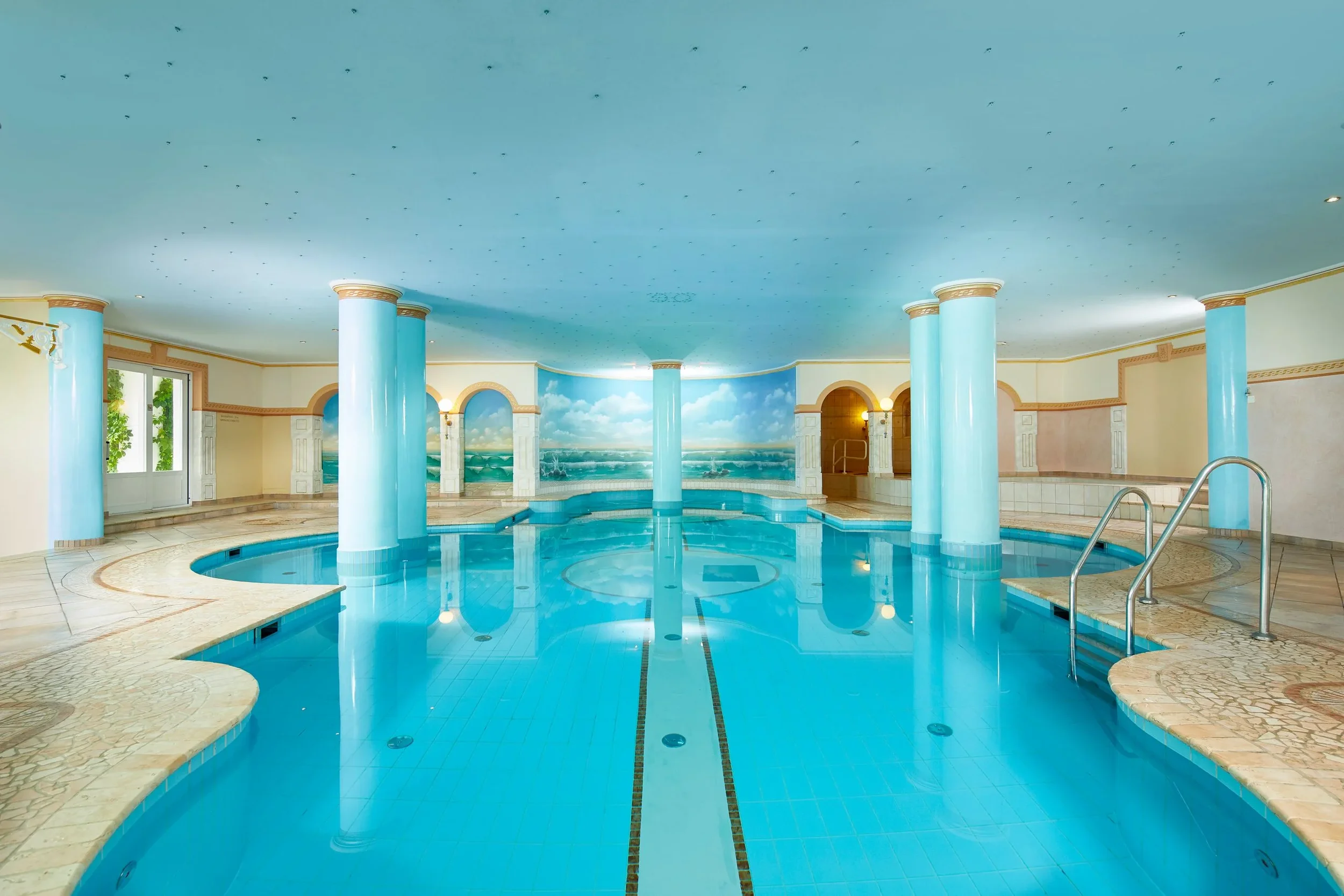Piscine intérieure du spa du Grand Hotel Zell am See avec colonnes et ambiance détente – Spa et bien-être pour séminaire – Aylo Montagne