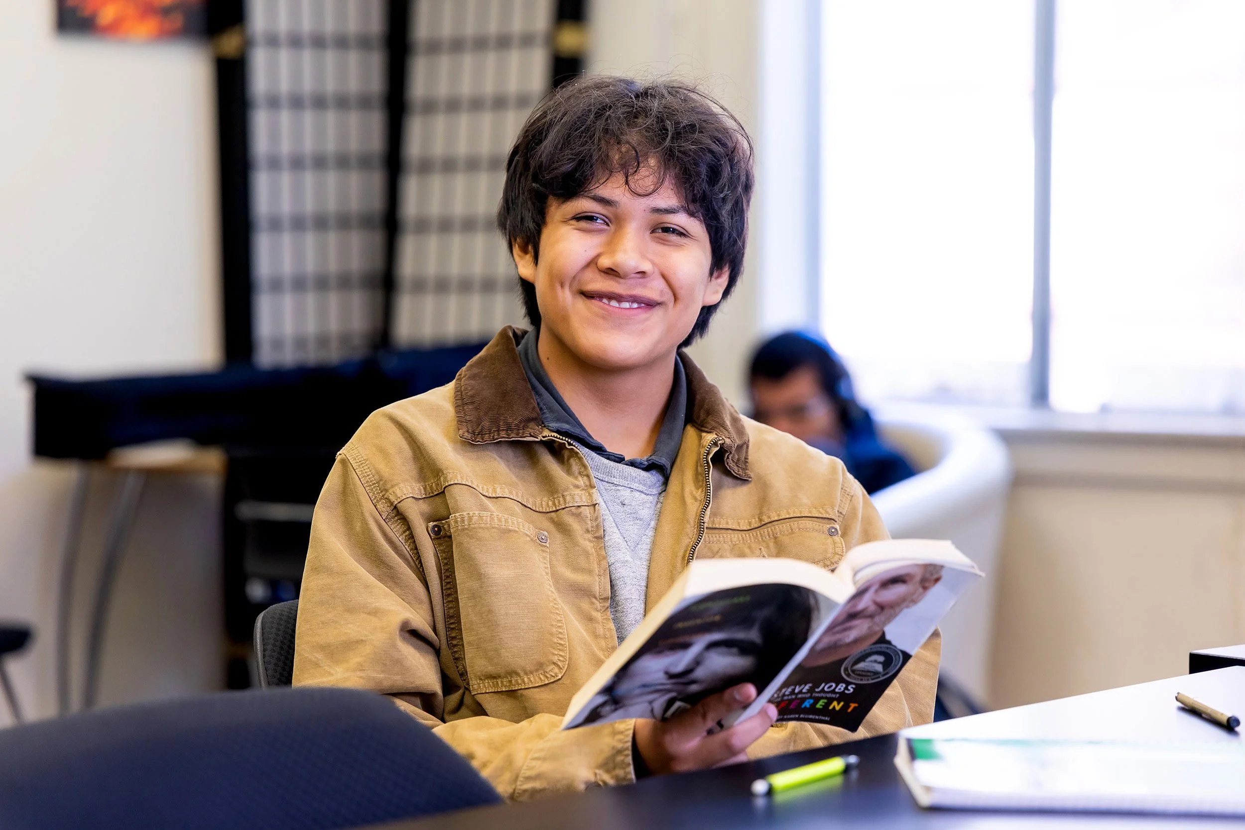 Smiling student reads book in class