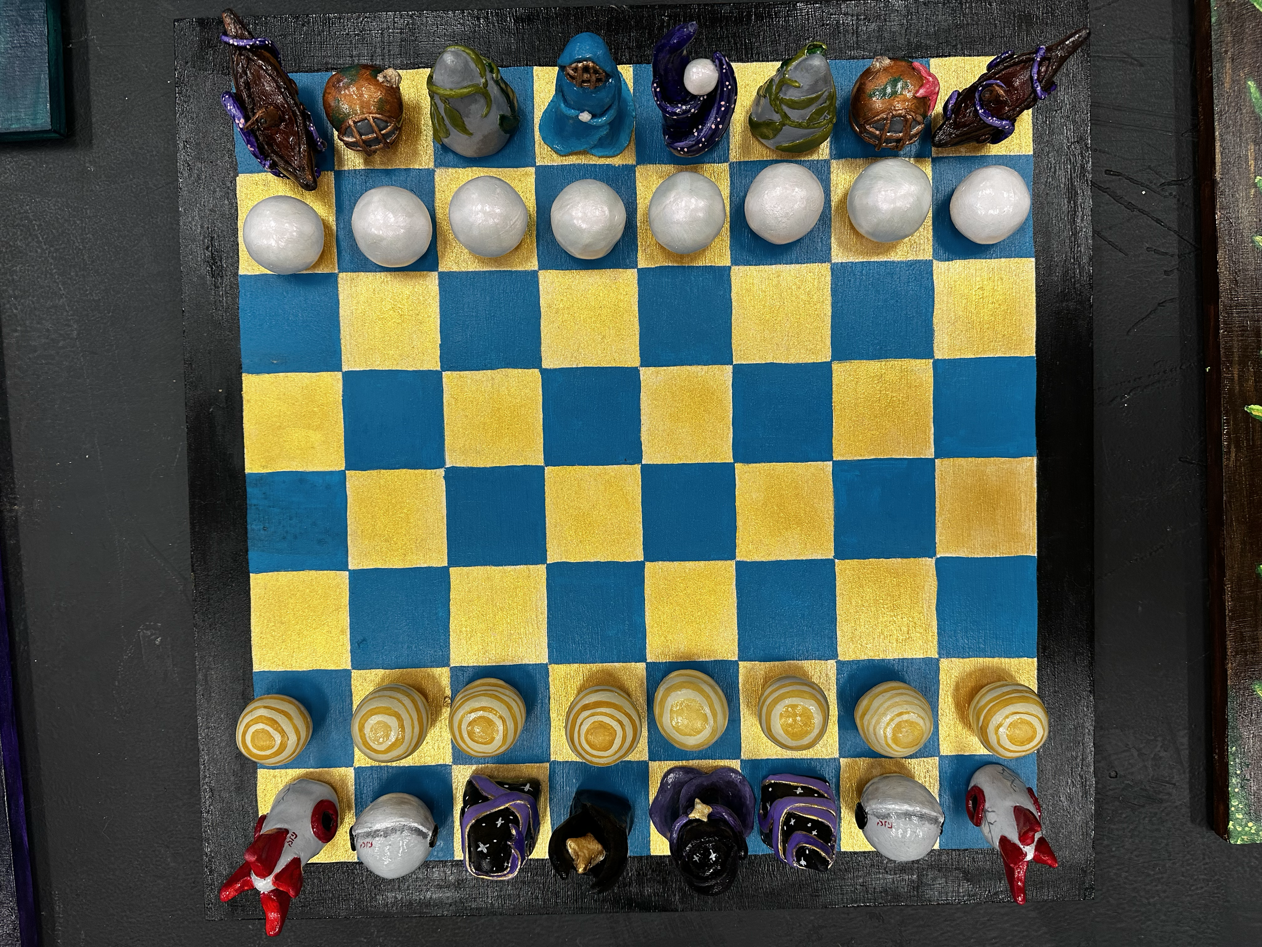A chessboard with various decorative chess pieces, some resembling animals, and a row of white and yellow pawns.
