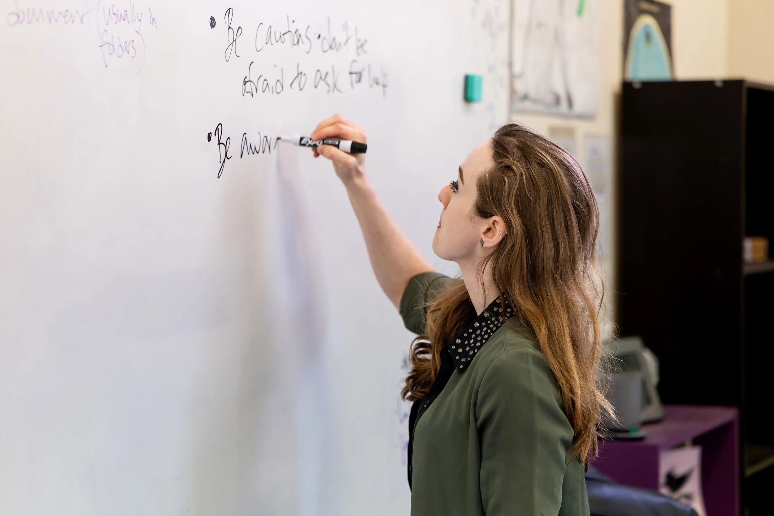 Compass teacher writes lessons on dry erase board
