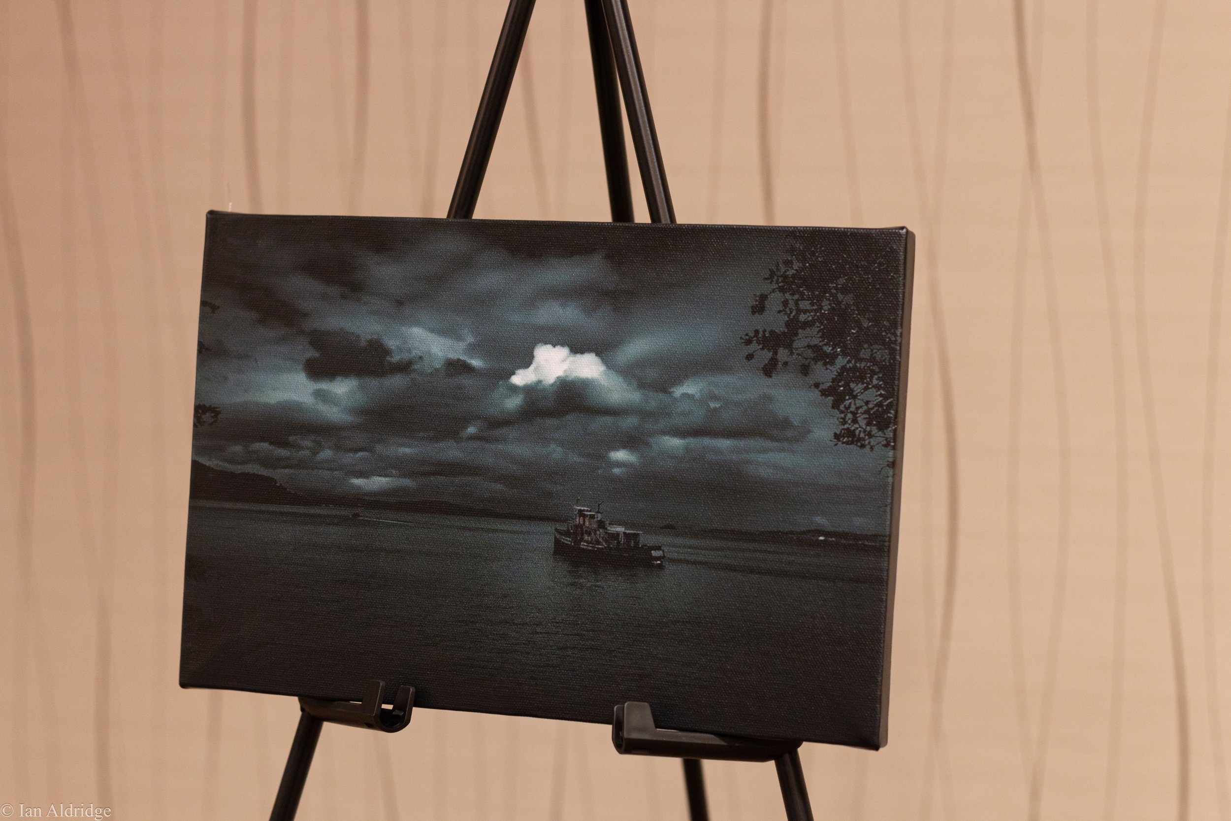 Canvas print of a black and white photograph of a boat on a dark cloudy sky.