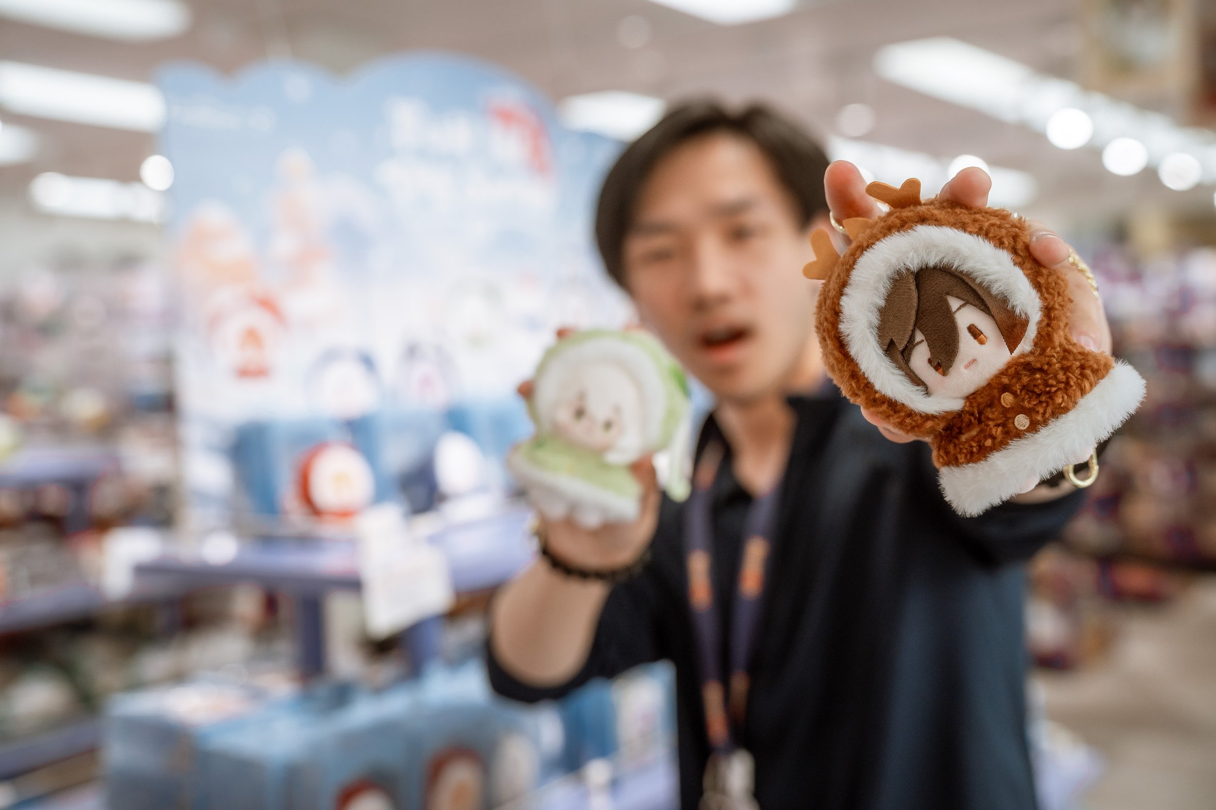 Person holding up a plush reindeer Christmas stocking in a store aisle with holiday decorations and items in the background.