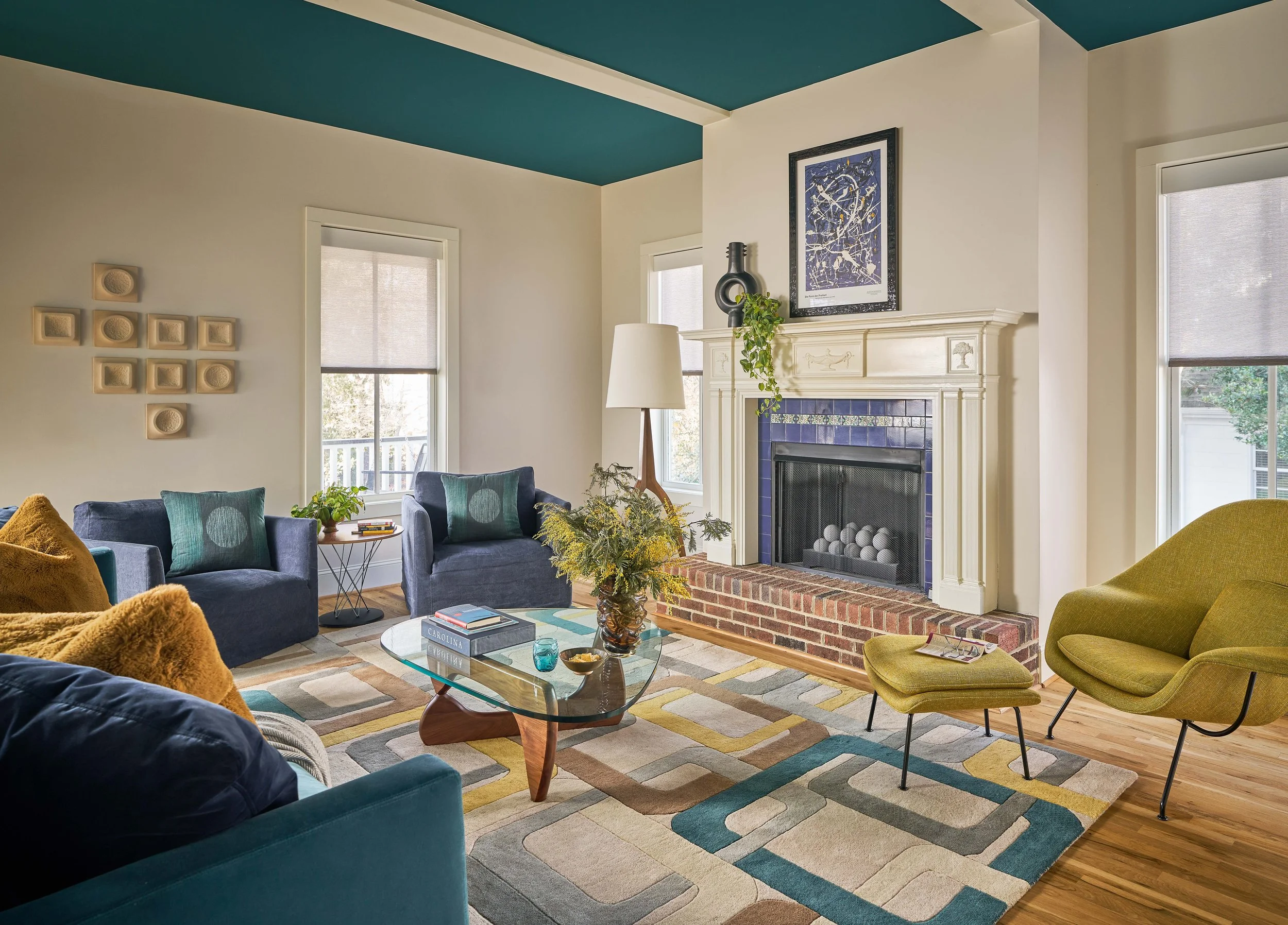 interior design for renovation cat french design mid-century-modern living room with mid-century modern couch coffee table and geometric rug with teal ceiling and fireplace with blue surround cat french design chapel hill interior designer
