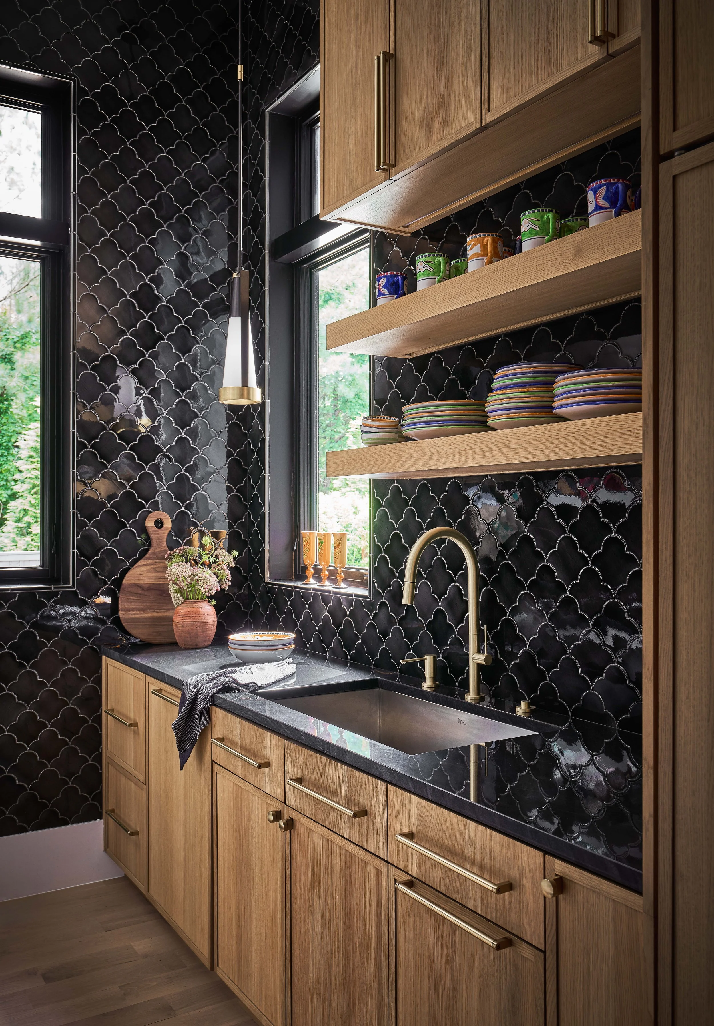 scullery kitchen with black floor to ceiling tile warm wood cabinetry open shelving and gold kitchen hardware with gold and black kitchen sconce in a durham custom home interior design cat french design luxury interior design durham