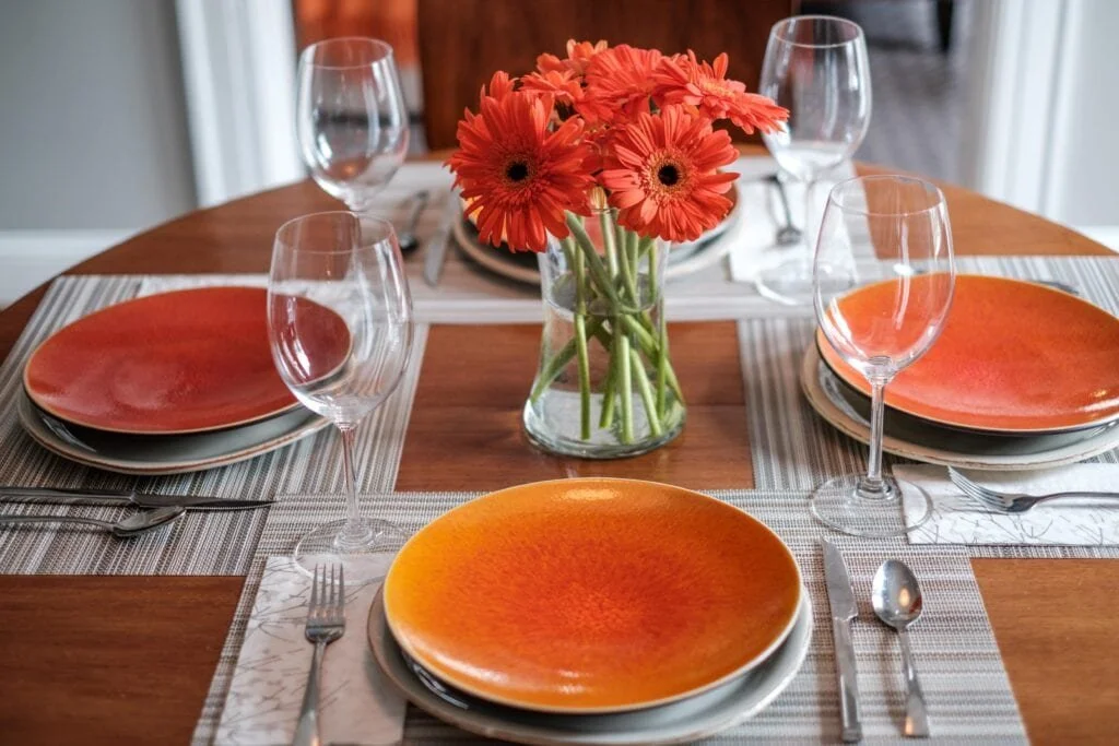 orange plates and flowers on a dining room table designed by cat french design in chapel hill nc