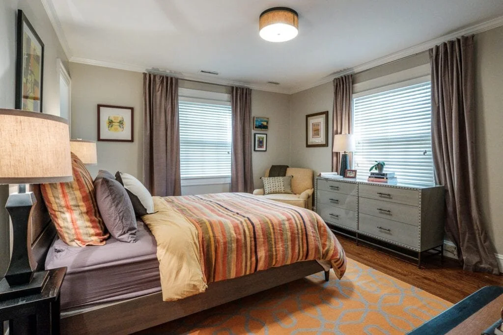 bedroom with orange color linens and rug by cat french design in chapel hill nc