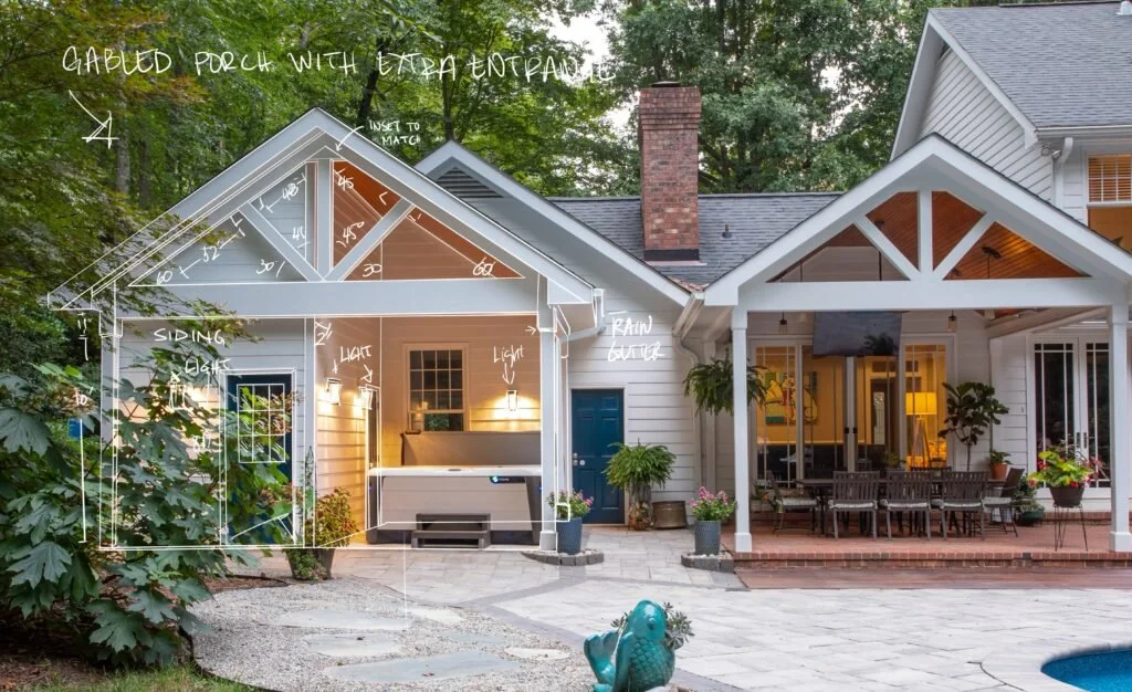view of back of a white house with gabled roof and blue doors with a brick patio dining table hot tub custom chapel hill home design