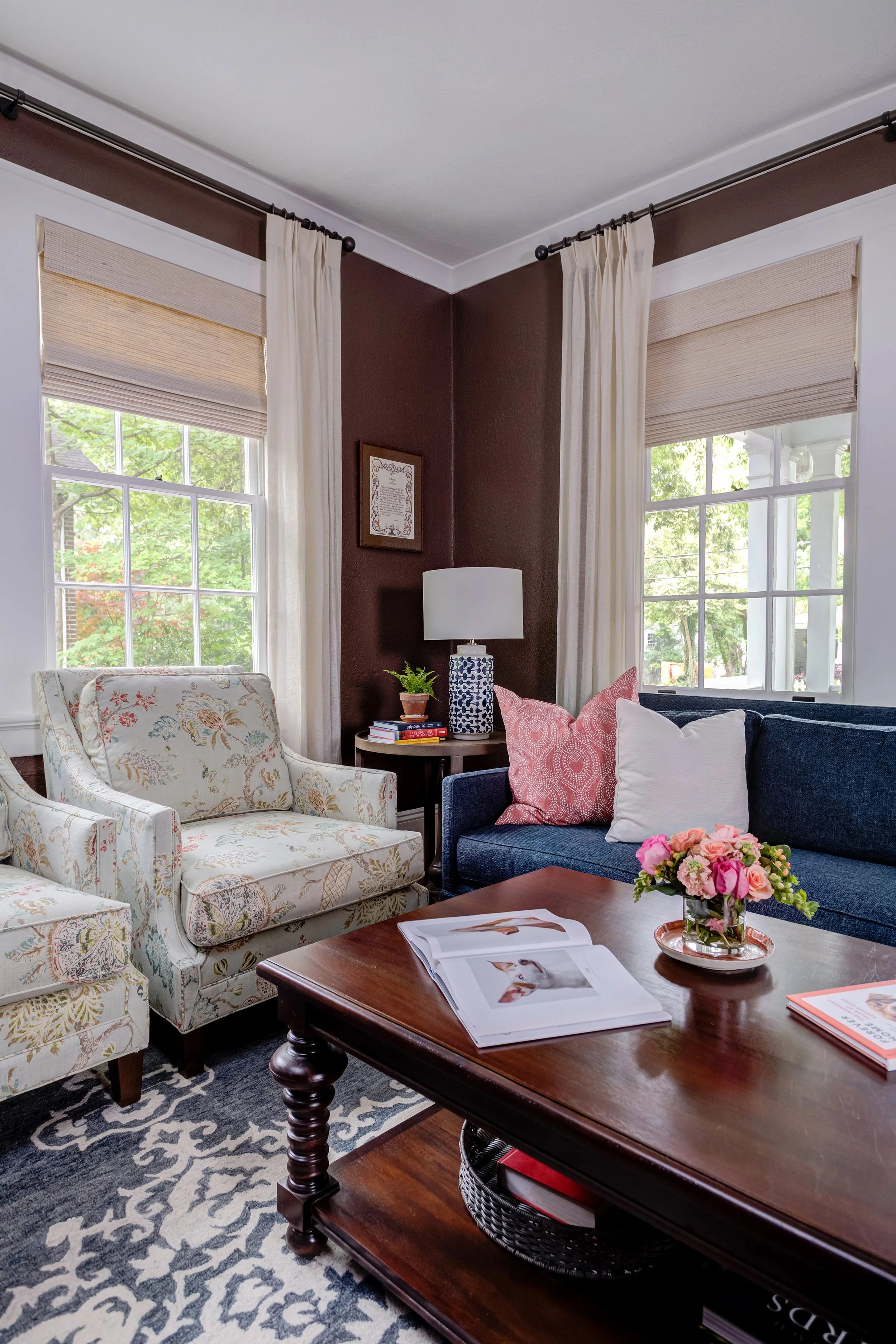 matching armchairs floral pattern and blue couch in den with chocolate brown wall paint designed by cat french design chapel hill interior designer durham interior designer